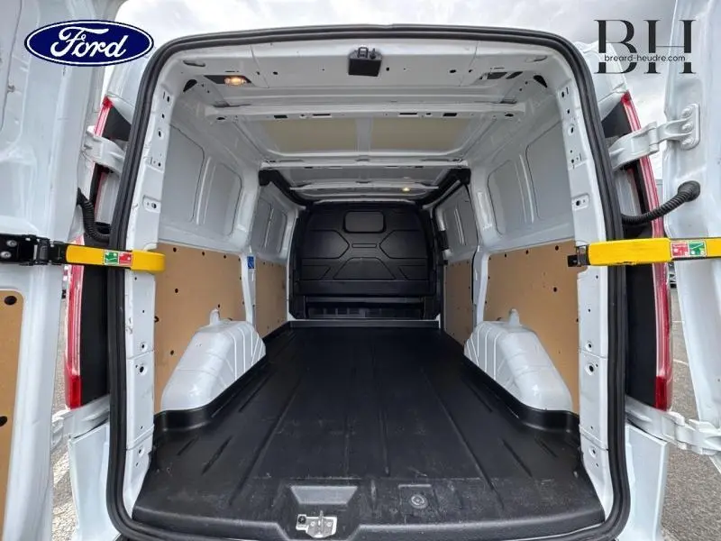Vue arrière ouverte du fourgon blanc Ford Transit Custom 2023 montrant l'espace de chargement vide avec plancher noir et cloison pleine.