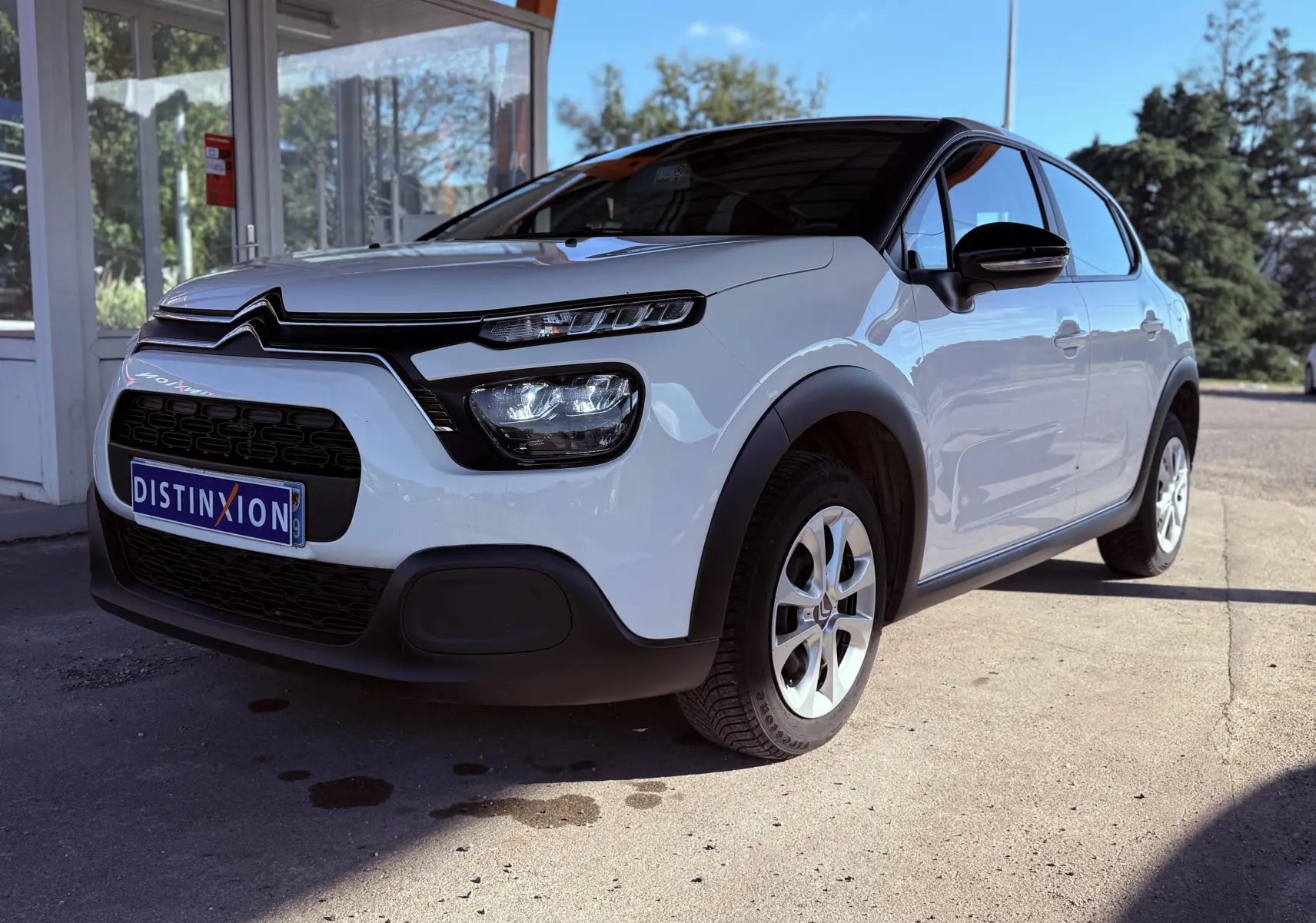 Citroën C3 blanche vue 3/4 avant droit, avec toit noir et calandre distinctive noire.