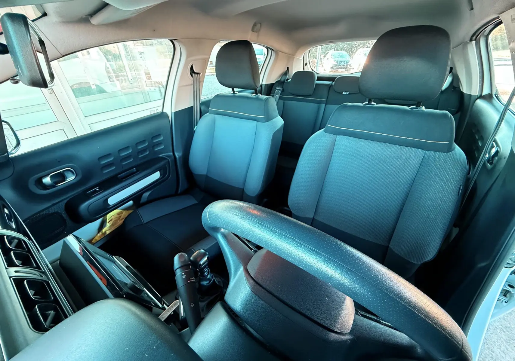 Vue intérieure côté conducteur de la Citroën C3 2021 avec sièges tissu gris-noir et volant noir.