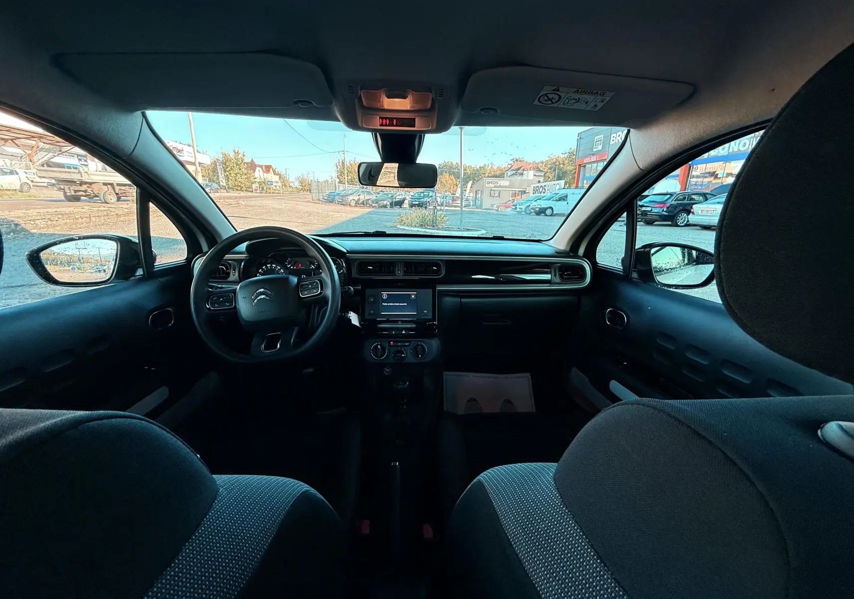 Vue intérieure avant du tableau de bord et volant d'une Citroën C3 1.5 BlueHDi 2021 avec sièges tissu gris-noir.