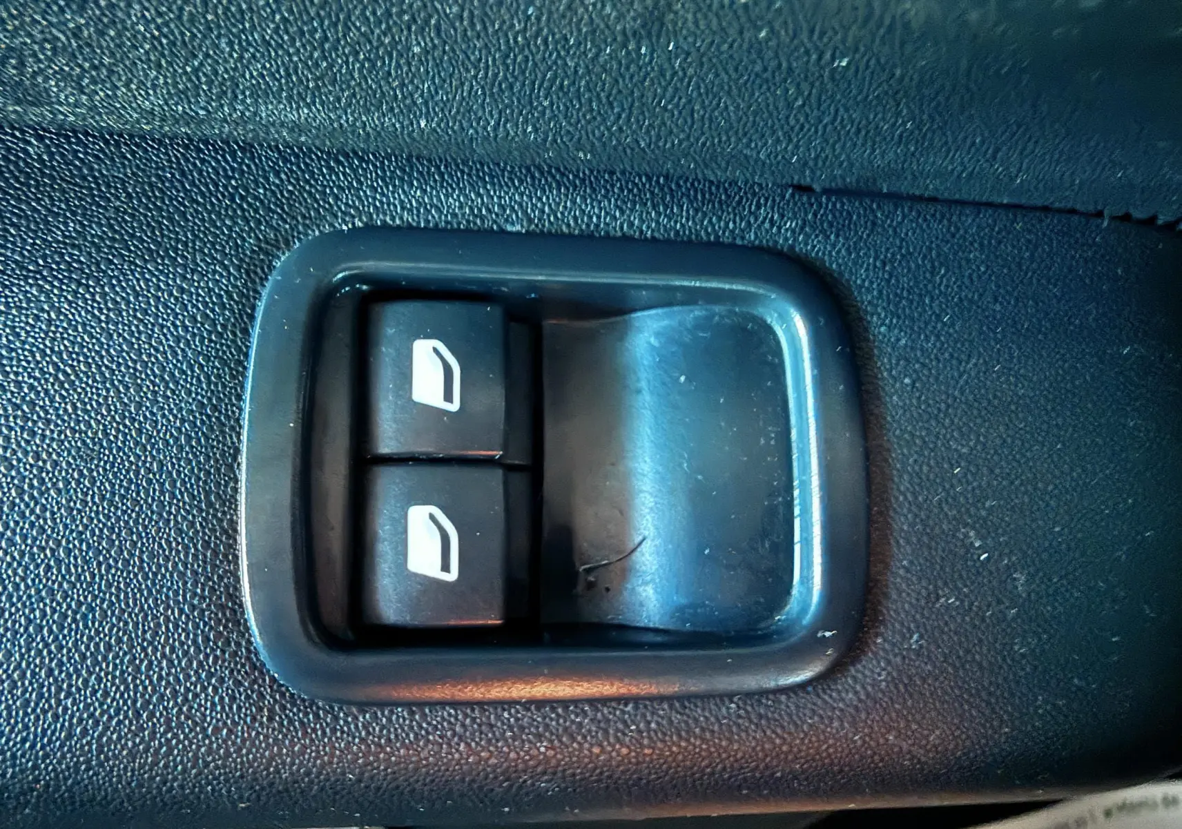 Gros plan sur les boutons de commande des vitres électriques côté conducteur d'une Citroën C3 blanche de 2021.