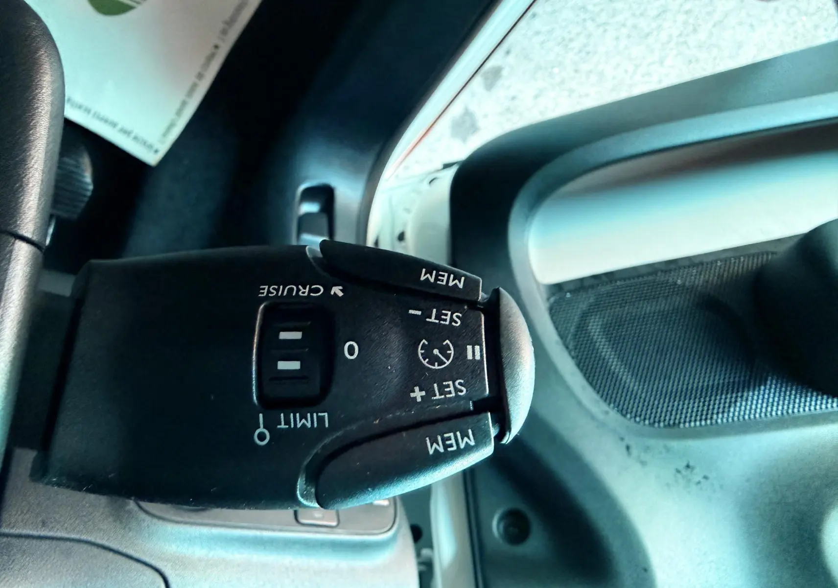 Gros plan sur la commande de régulateur de vitesse à gauche du volant dans une Citroën C3 blanche de 2021.