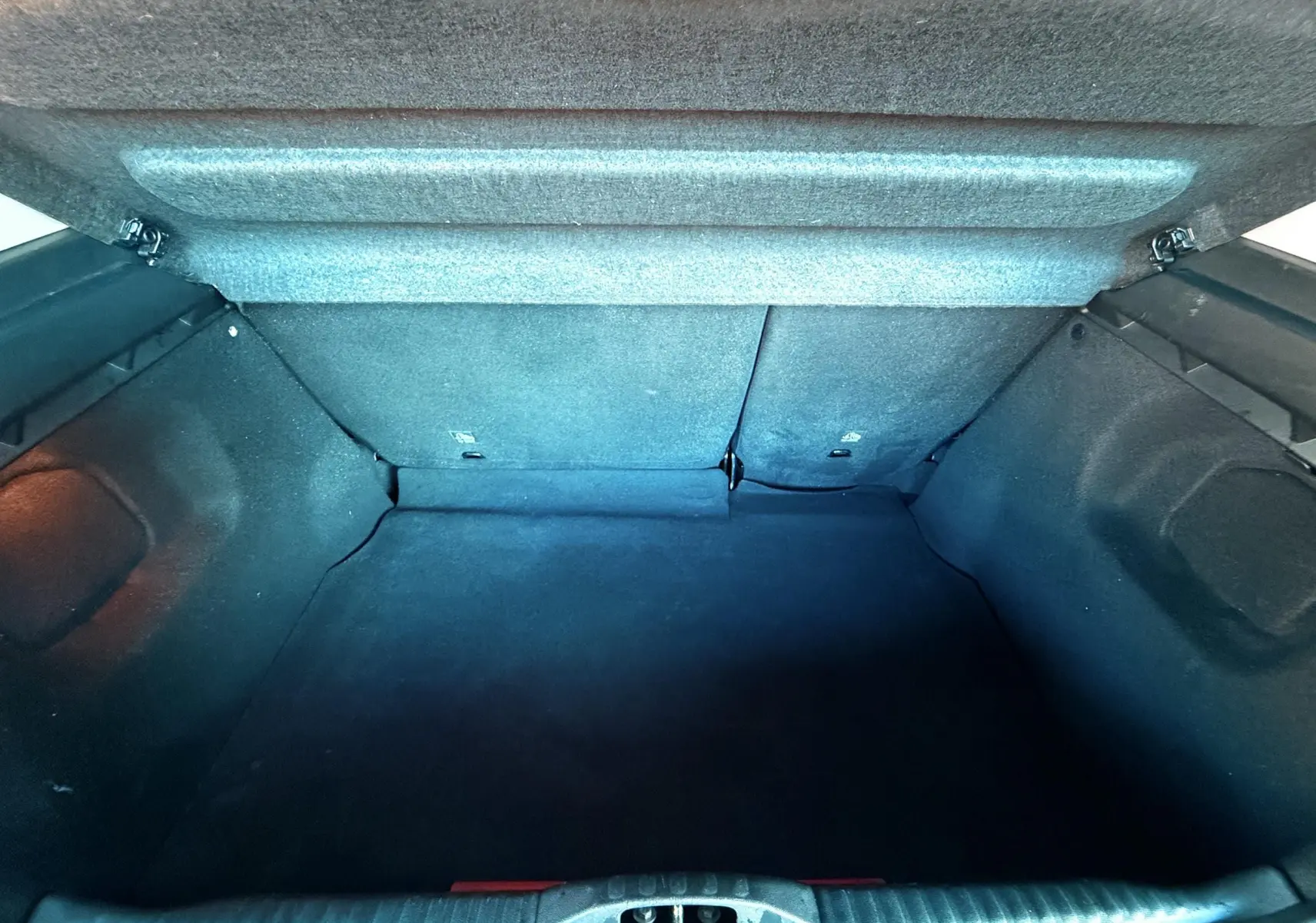 Coffre ouvert vu de l'arrière d'une Citroën C3 blanche 2021, espace de chargement vide et tapis noir.