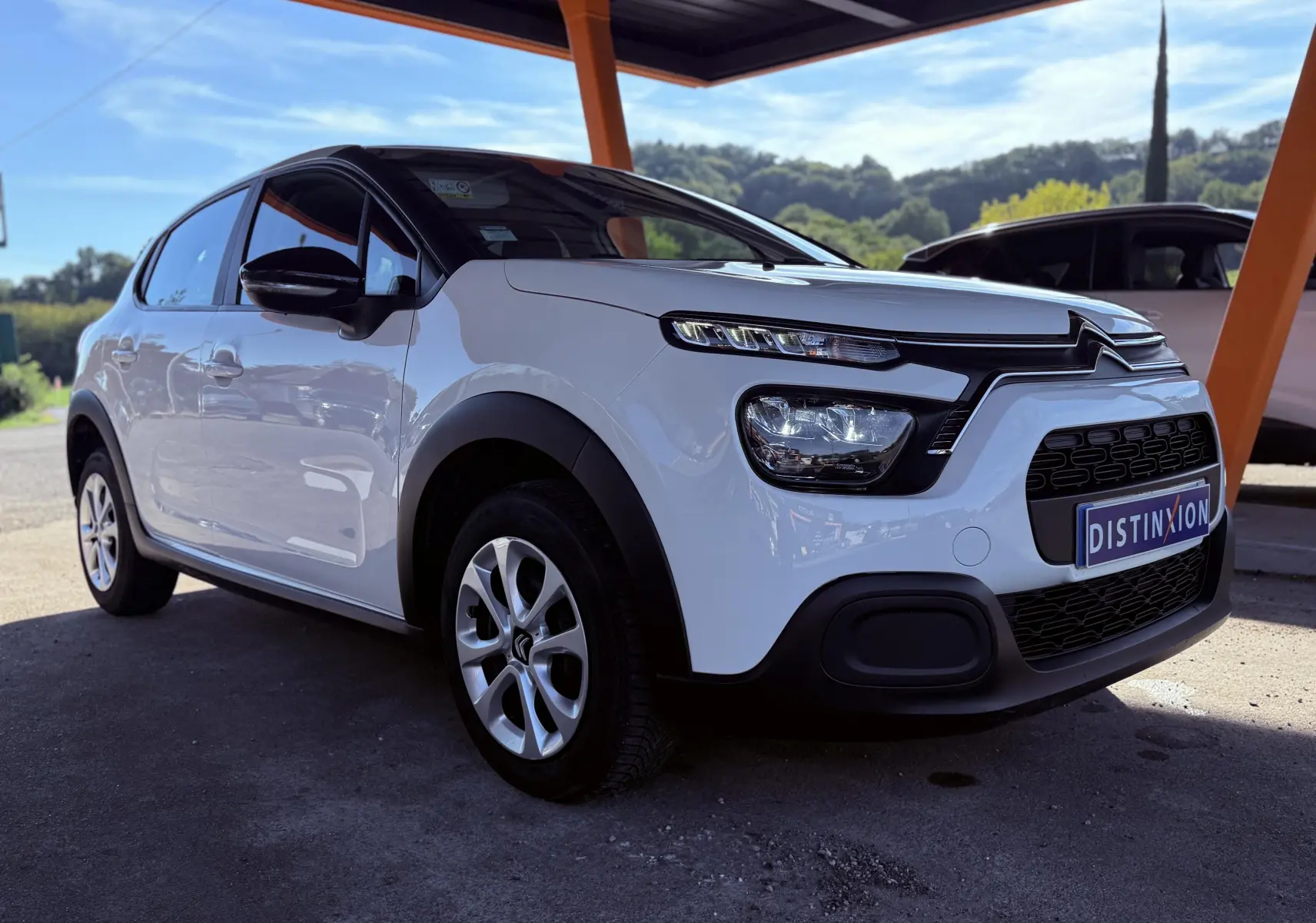 Citroën C3 blanche vue 3/4 avant droit sous abri, avec jantes alliage et détails noirs contrastants.
