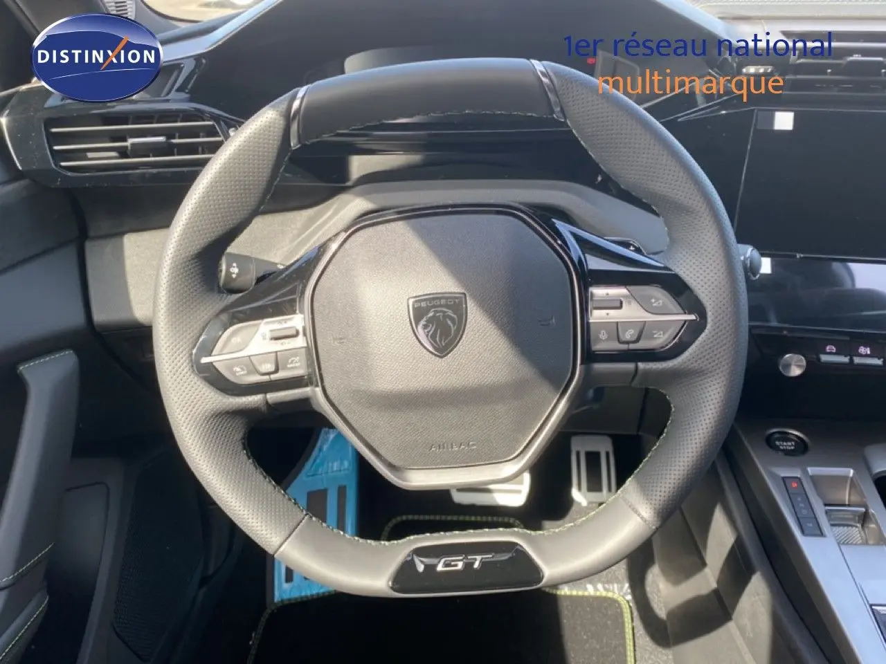 Volant cuir noir GT de Peugeot 308 Hybrid 145ch, vue frontale centrée sur les commandes intégrées et logo au centre.