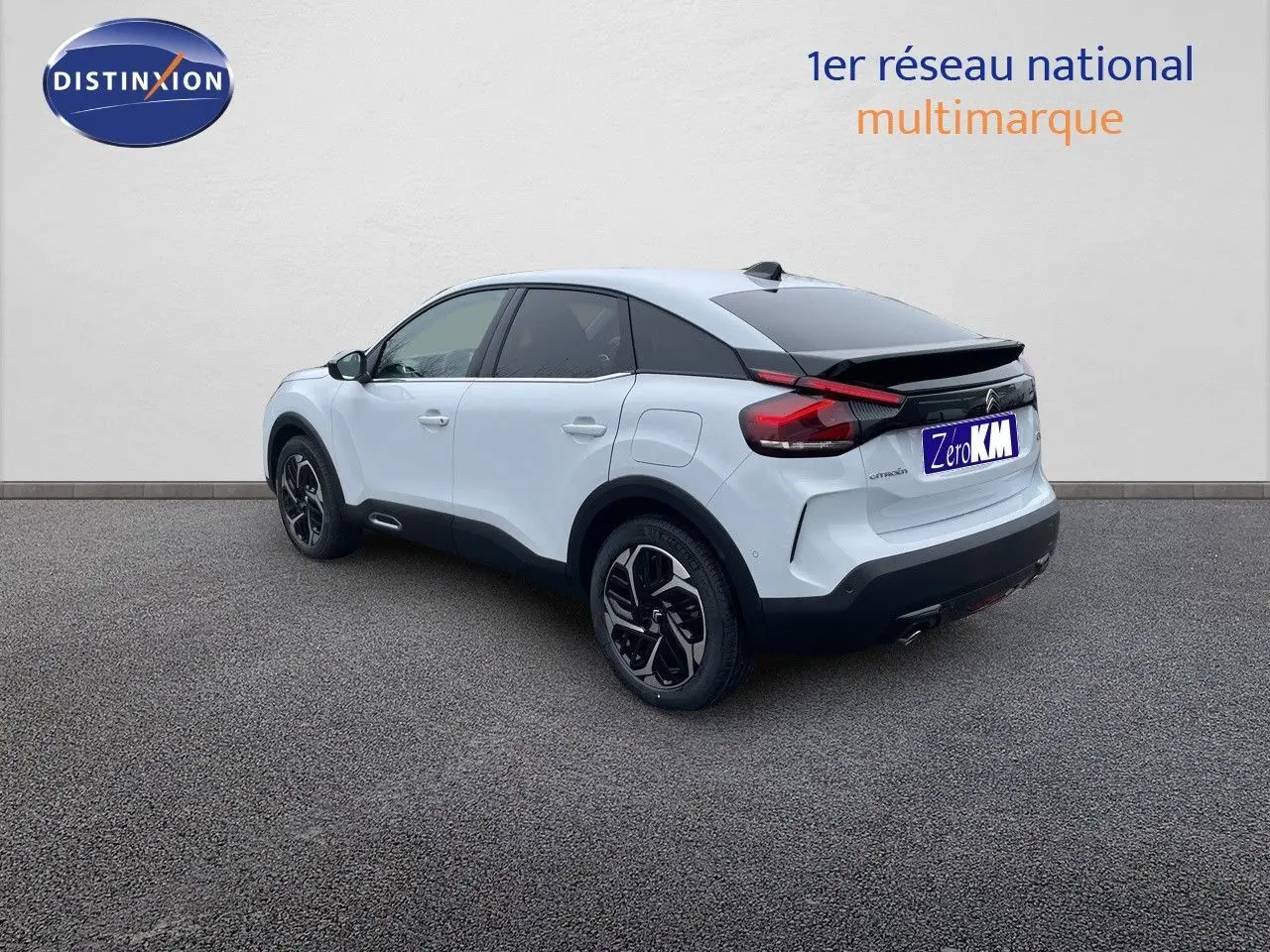 Citroën C4 blanc métal vue 3/4 arrière droit, avec toit noir et jantes bi-ton distinctives.