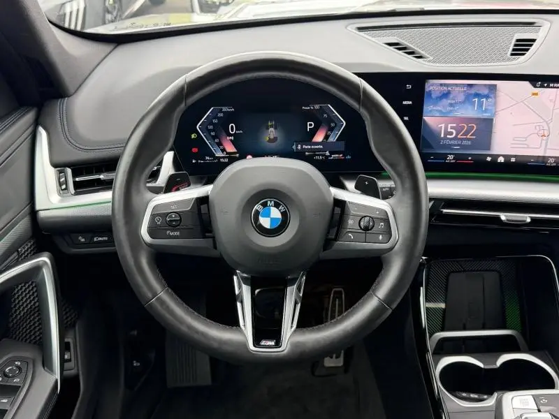 Vue intérieure centrée sur le volant cuir multifonction et l'écran numérique du BMW X1 XDrive20d Spacesilber métal 2025.