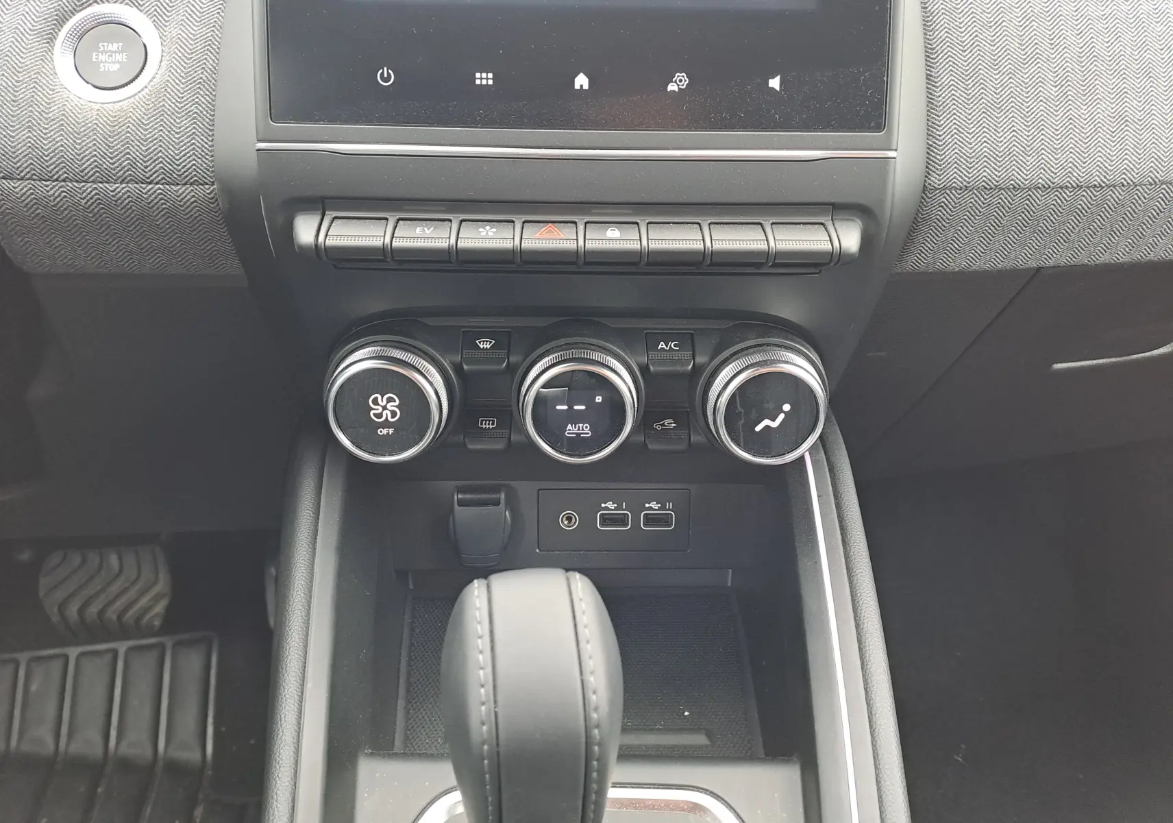 Vue rapprochée du tableau de bord de la Renault Clio V 2025, montrant les commandes de climatisation et la console centrale noire.