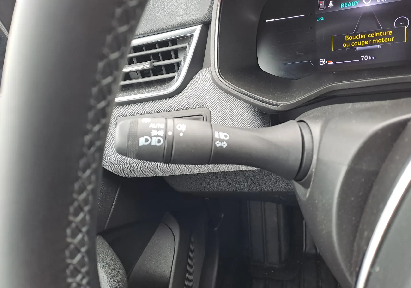 Gros plan sur la manette des feux à gauche du volant dans l'habitacle de la Renault Clio V hybride 2025.