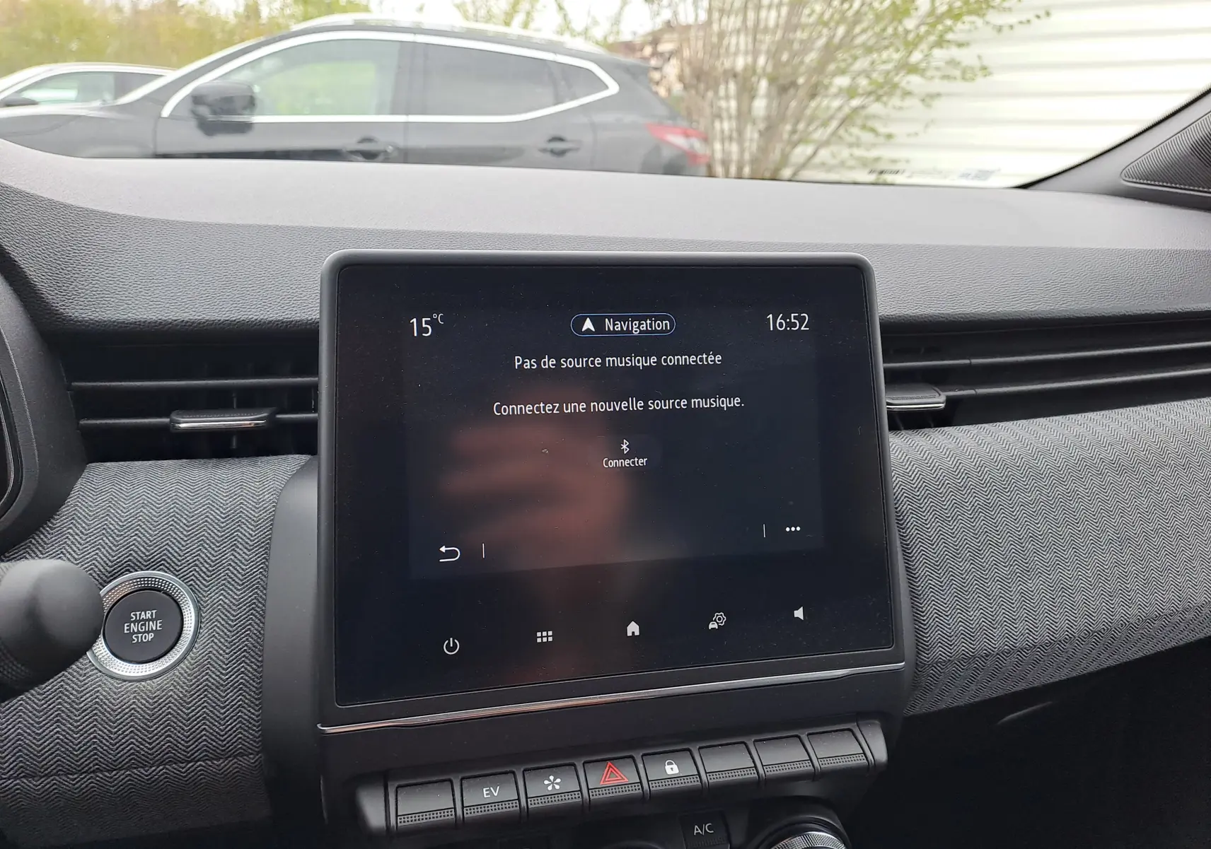 Vue intérieure centrée sur l'écran tactile et tableau de bord gris texturé de la Renault Clio V hybride 2025.
