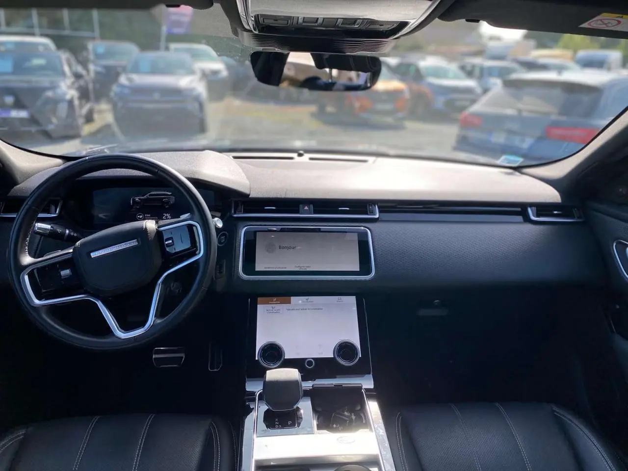 Intérieur du Range Rover Velar 2022 vu de face, tableau de bord noir avec écran tactile et volant multifonction.