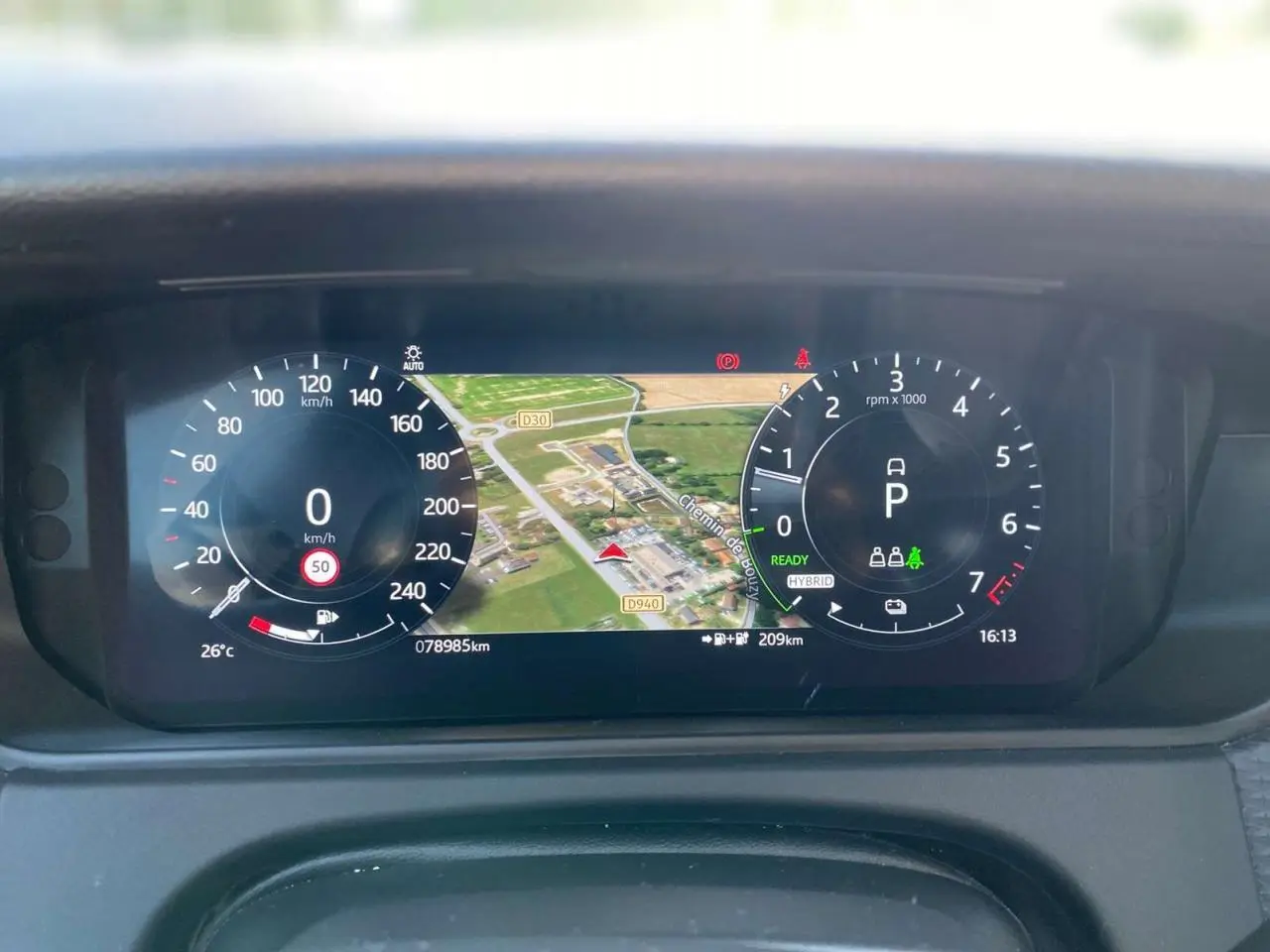 Tableau de bord numérique du Range Rover Velar gris, affichant vitesse, navigation et indicateurs hybrides.