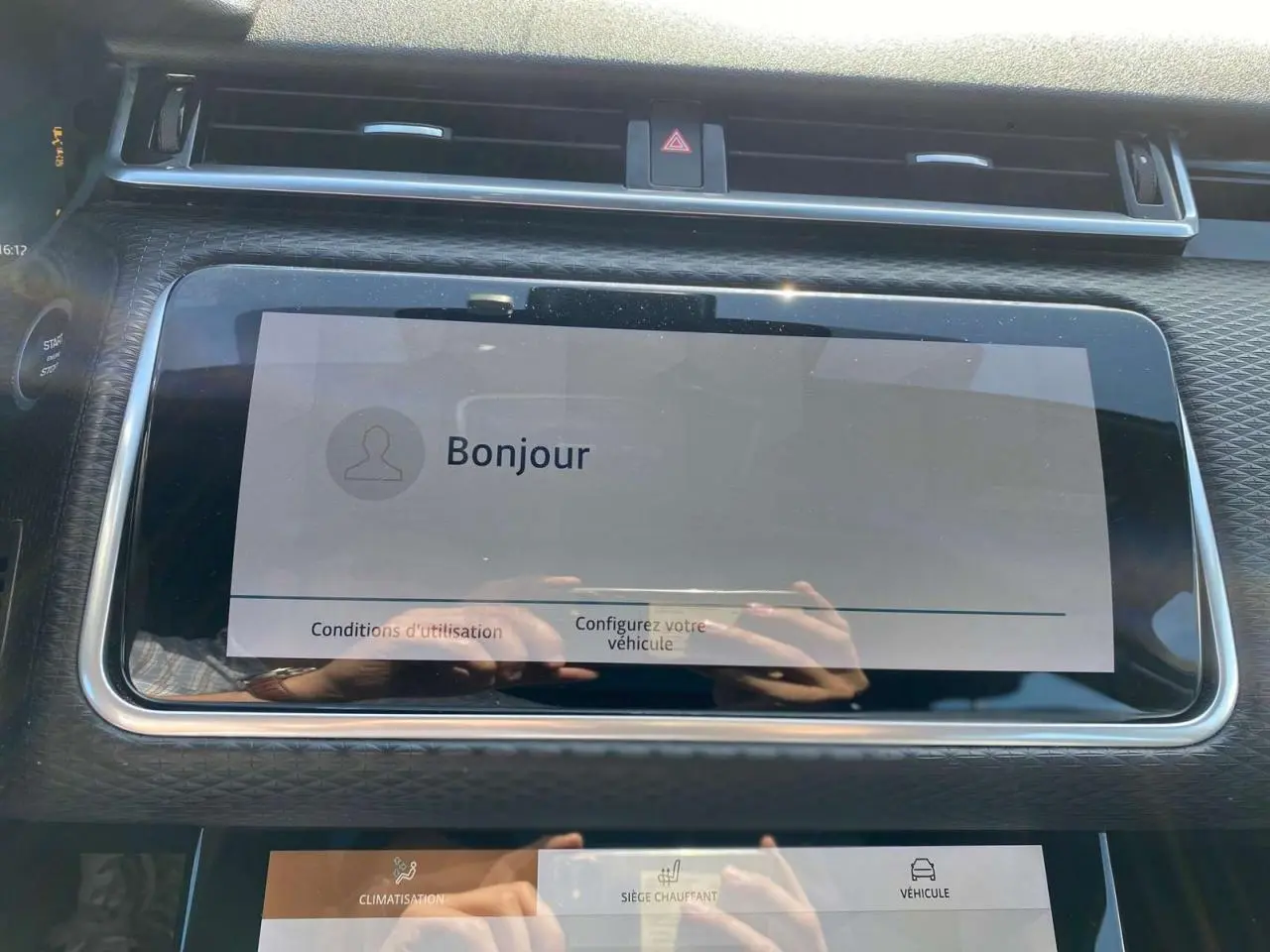 Écran tactile central affichant un message de bienvenue dans l'habitacle du Range Rover Velar gris Tempête, vue de face rapprochée.