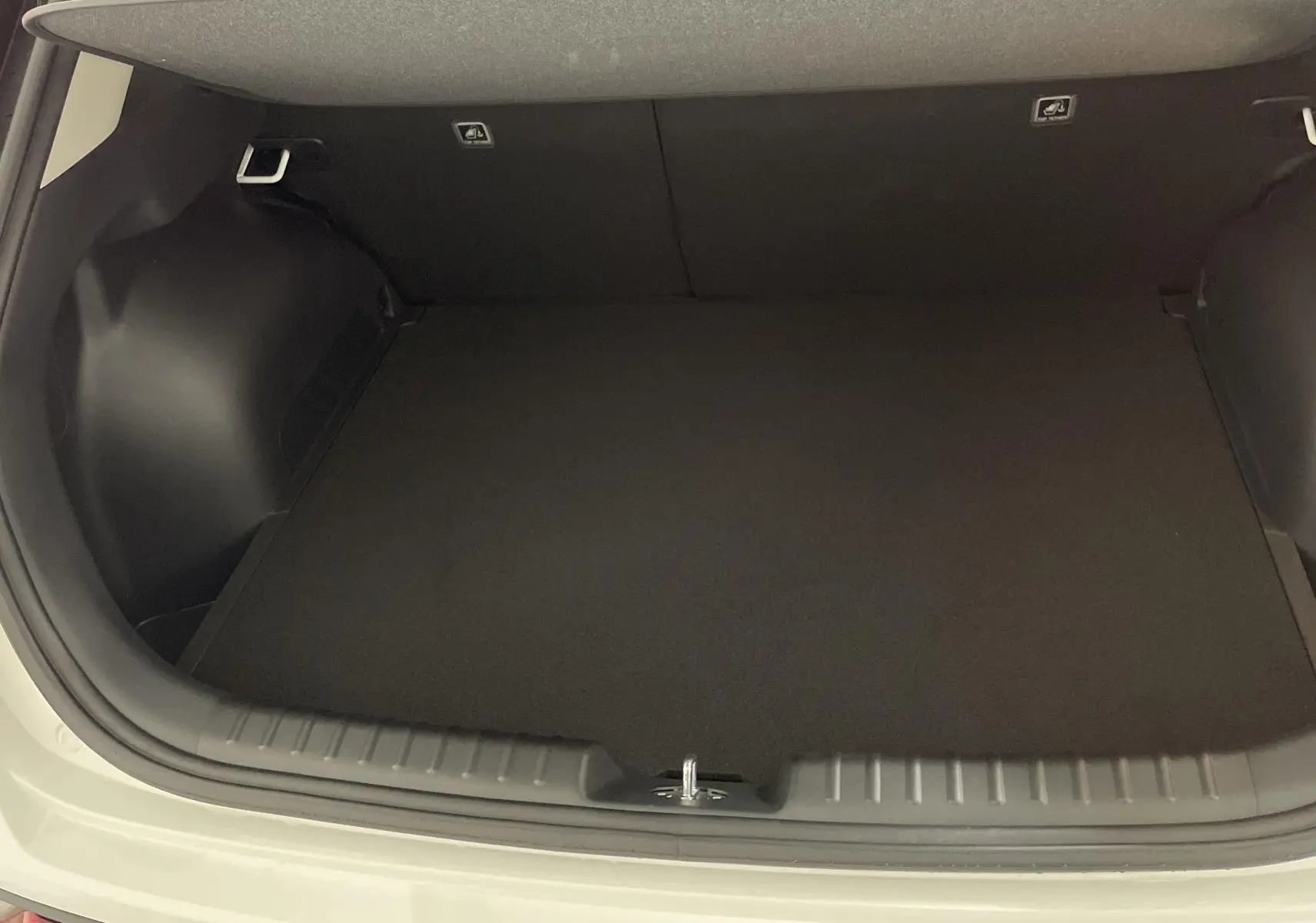 Coffre ouvert vu de l'arrière d'un KIA NIRO blanc 2025, montrant un espace de chargement propre et spacieux.