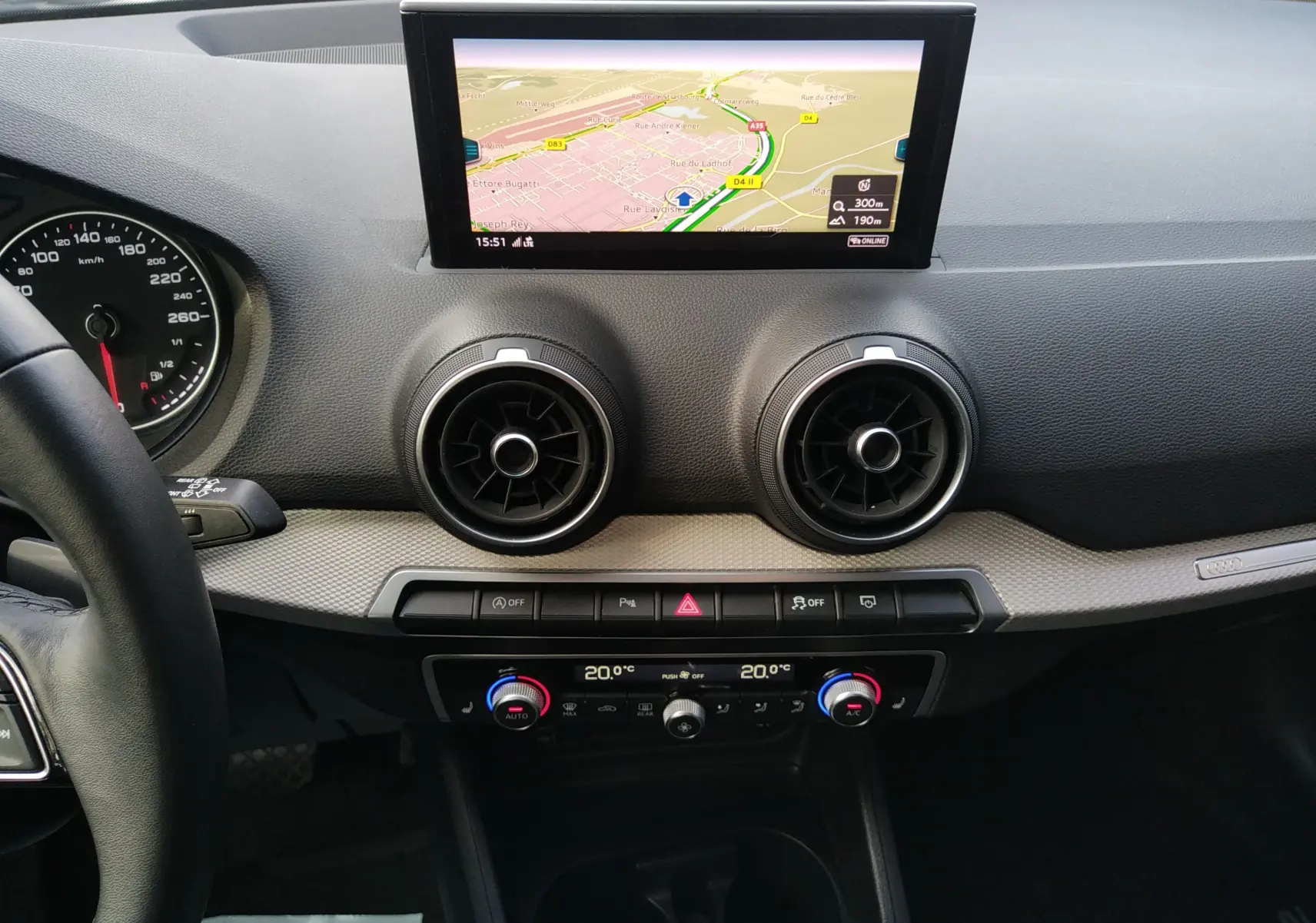 Tableau de bord de l'Audi Q2 35 TFSI S-Line 2023 avec écran GPS et commandes de climatisation visibles de face.