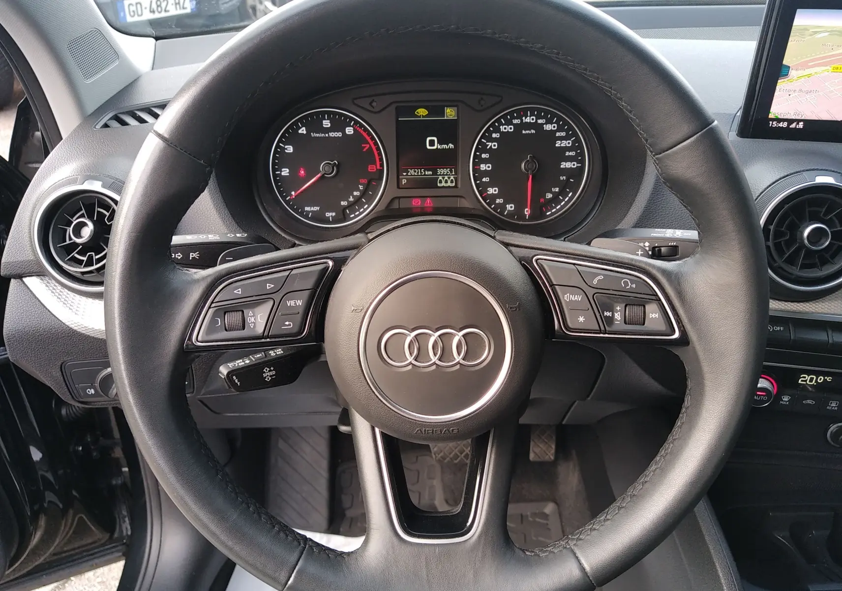 Vue rapprochée du volant en cuir noir de l'Audi Q2 35 TFSI S-Line 2023 avec tableau de bord et écran GPS visible.