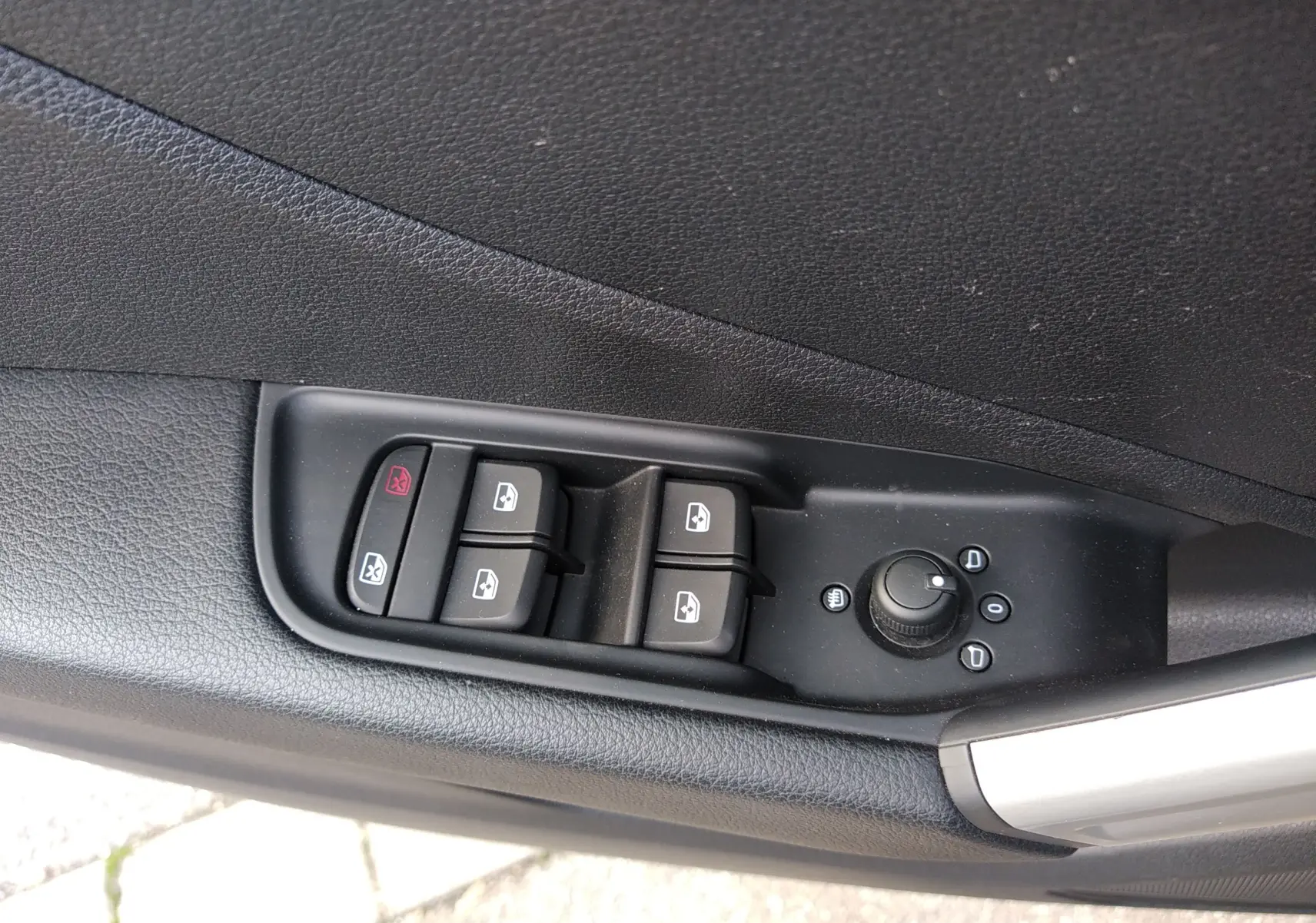 Commandes des vitres électriques et réglage des rétroviseurs sur la porte côté gauche d'un Audi Q2 noir Mito Metal 2023.