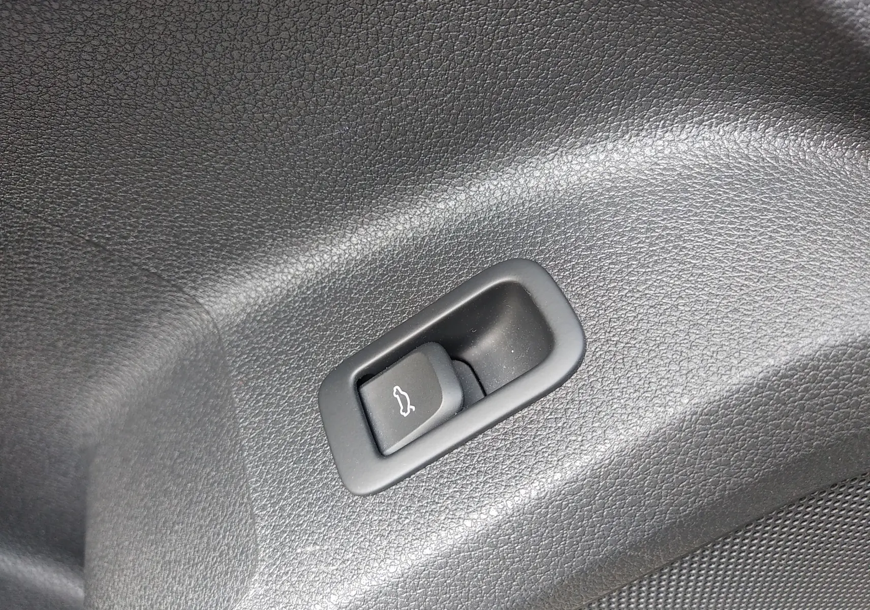 Bouton d'ouverture électrique du hayon sur le revêtement intérieur noir du coffre de l'Audi Q2 35 TFSI S-Line 2023.