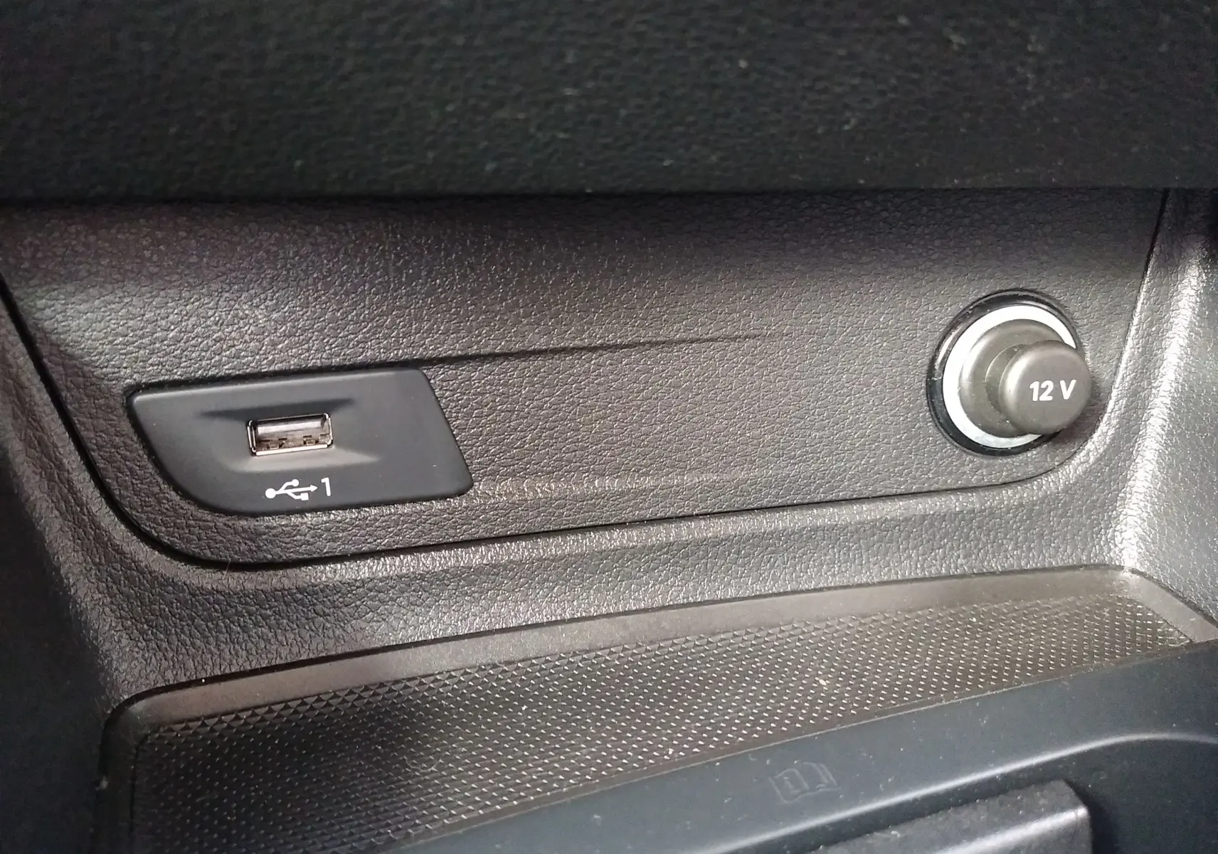 Prise USB et allume-cigare 12V en gros plan sur la console centrale noire d'un Audi Q2 2023.