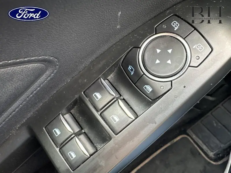 Gros plan sur les commandes électriques des vitres et rétroviseurs côté conducteur d'une Ford Focus noire Shadow de 2019.