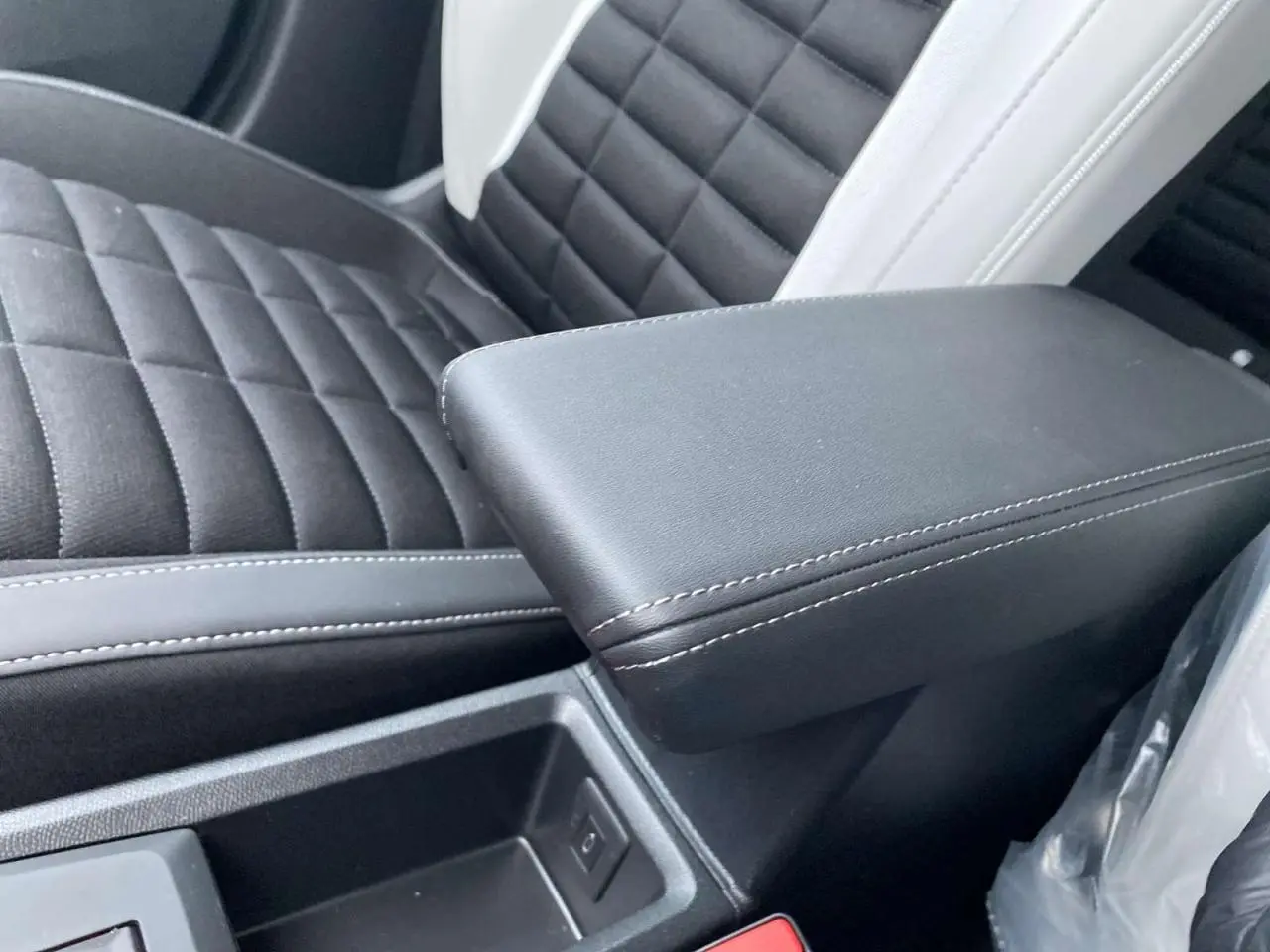 Accoudoir central noir avec surpiqûres blanches et siège avant en tissu noir et blanc du Citroën C3 Aircross.