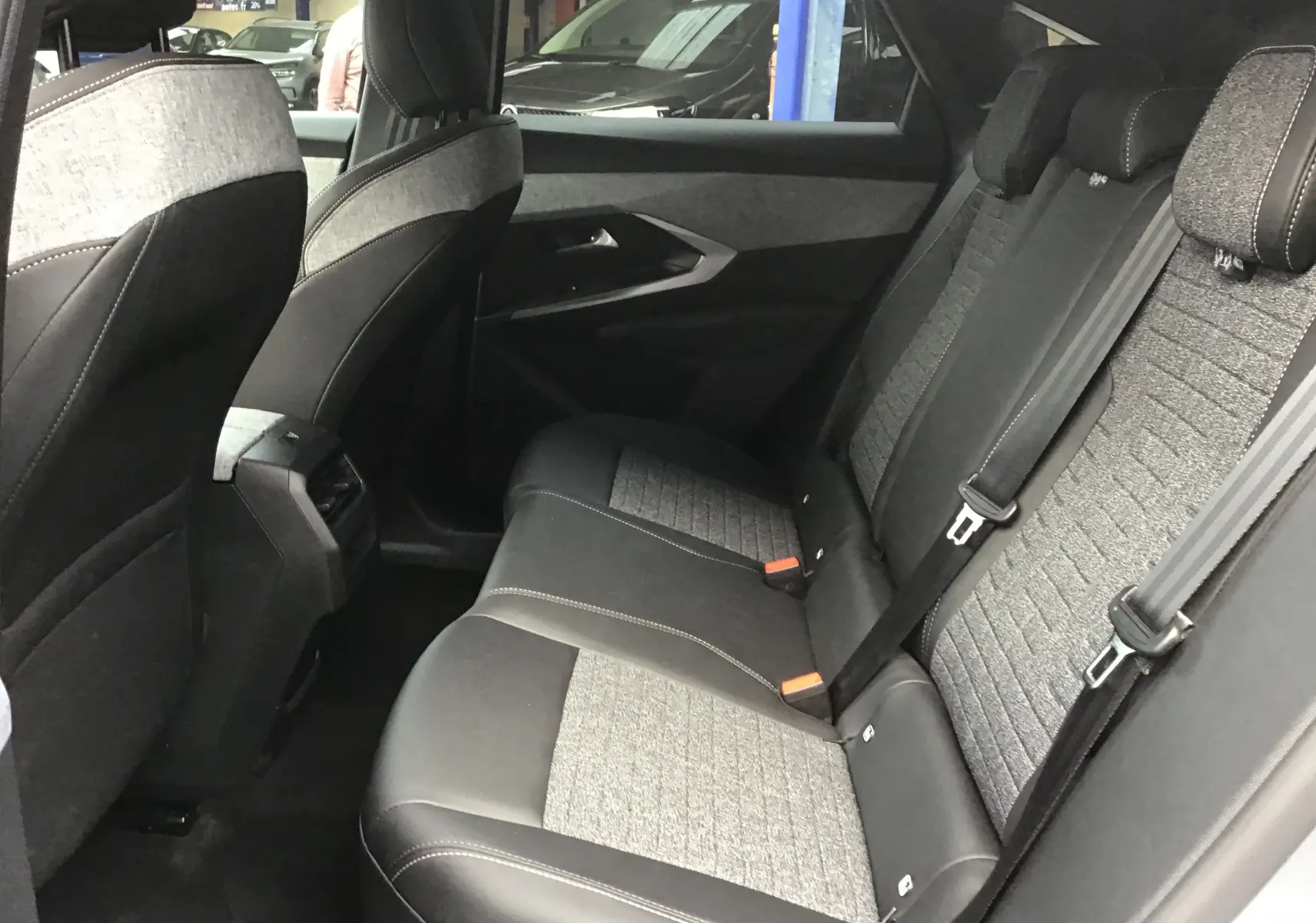 Vue intérieure côté droit des sièges arrière du Peugeot 3008 1.2 Hybrid 145 Allure avec sellerie tissu et cuir gris.