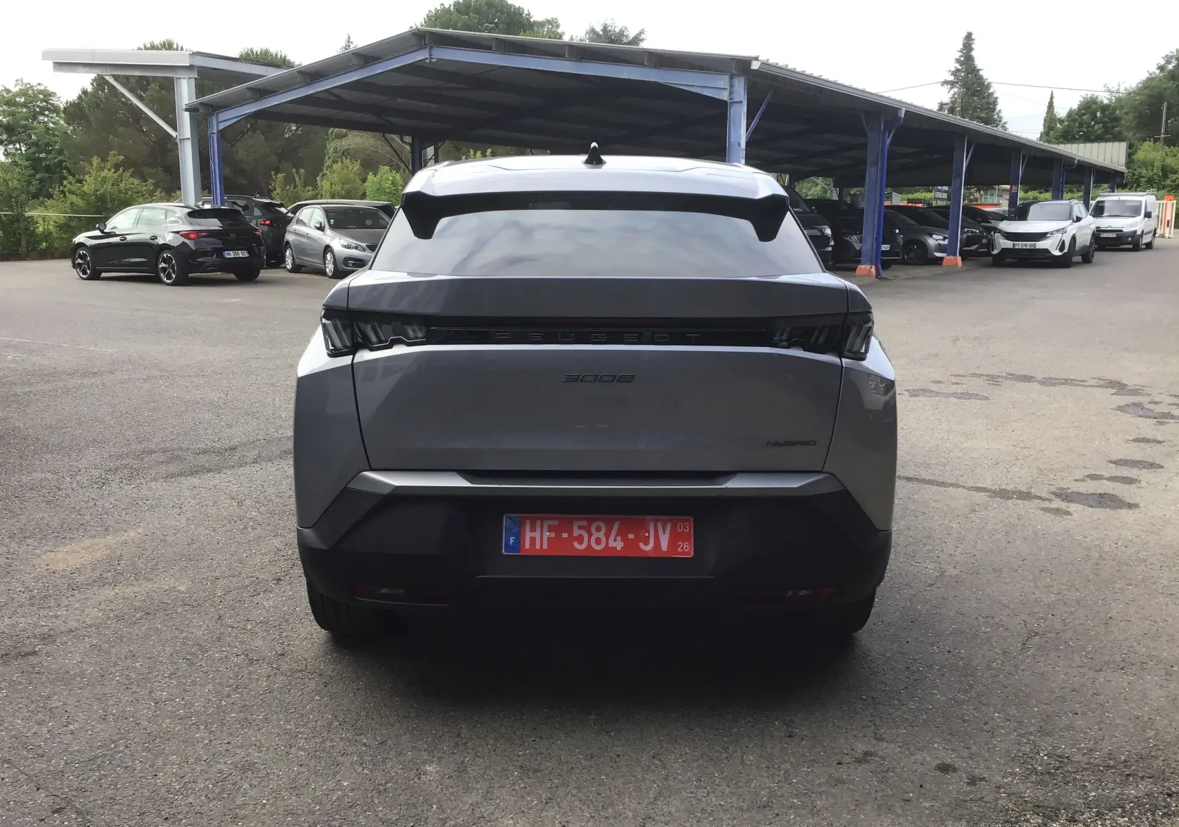 Vue arrière d'un Peugeot 3008 gris Artense 2026, avec feux noirs et logo Peugeot en relief sur le hayon.