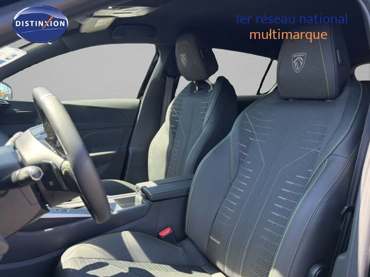 Intérieur de la Peugeot 308 Hybrid 145ch GT 2026, vue côté conducteur, sièges noirs avec surpiqûres vertes et logo Peugeot brodé.
