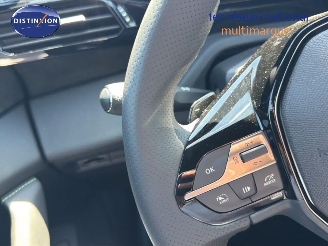 Gros plan sur le volant perforé avec commandes intégrées, intérieur noir de la Peugeot 308 Hybrid 2026.