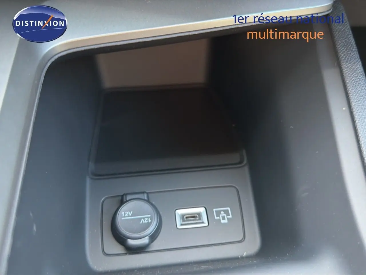 Vue rapprochée de la prise 12V et port USB dans le compartiment central d'une Peugeot 308 Hybrid 2026 noir perle métallisé.