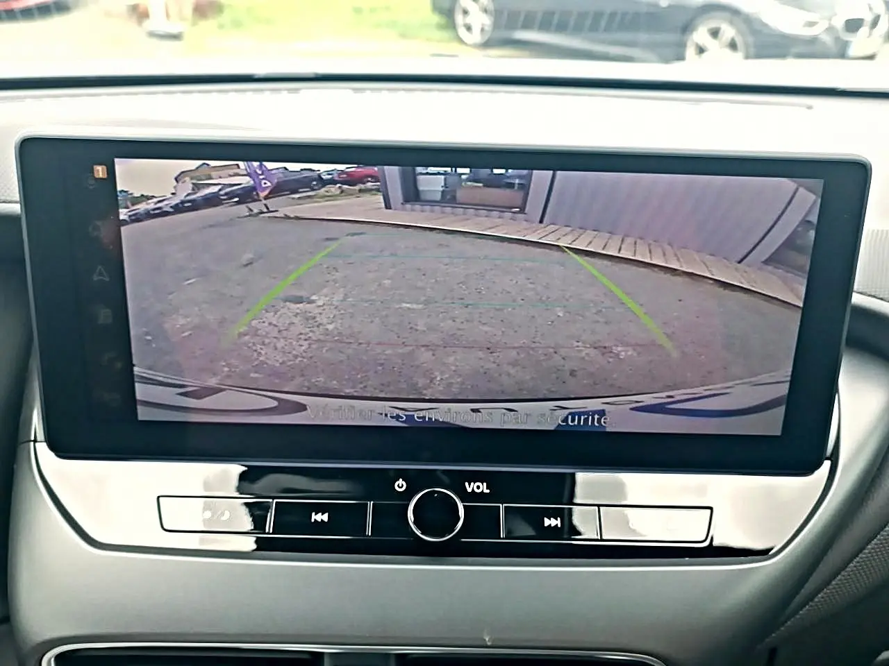 Écran tactile intérieur montrant la caméra de recul d'un Nissan Juke gris, vue frontale du tableau de bord.