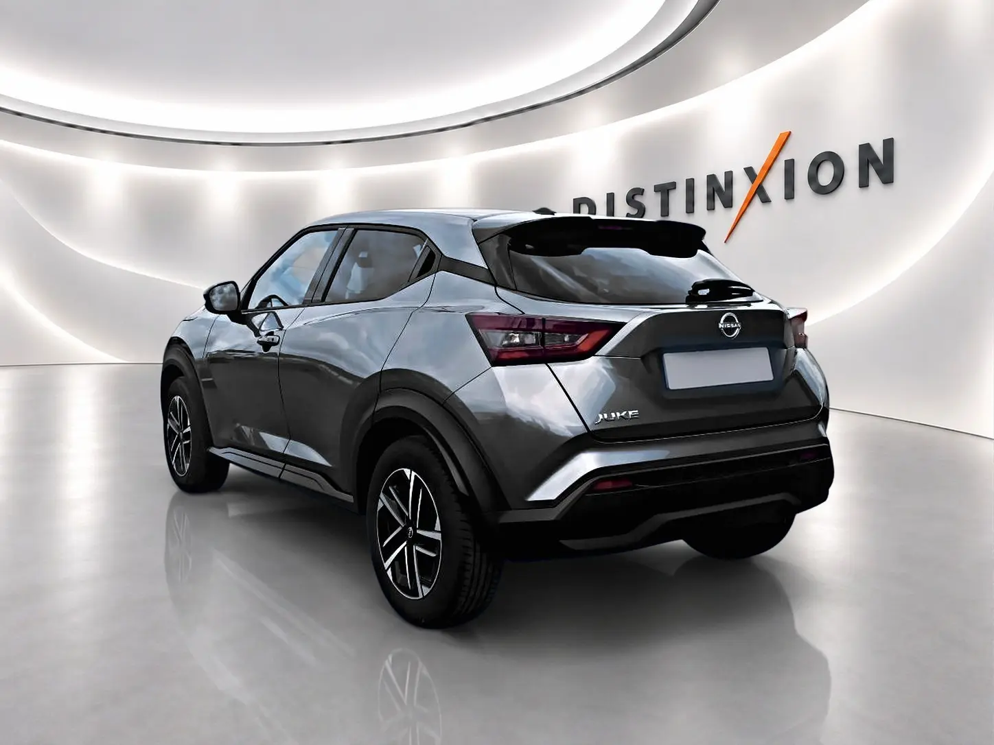 Nissan Juke gris en 3/4 arrière droit dans un showroom lumineux avec jantes alu et feux arrière LED.
