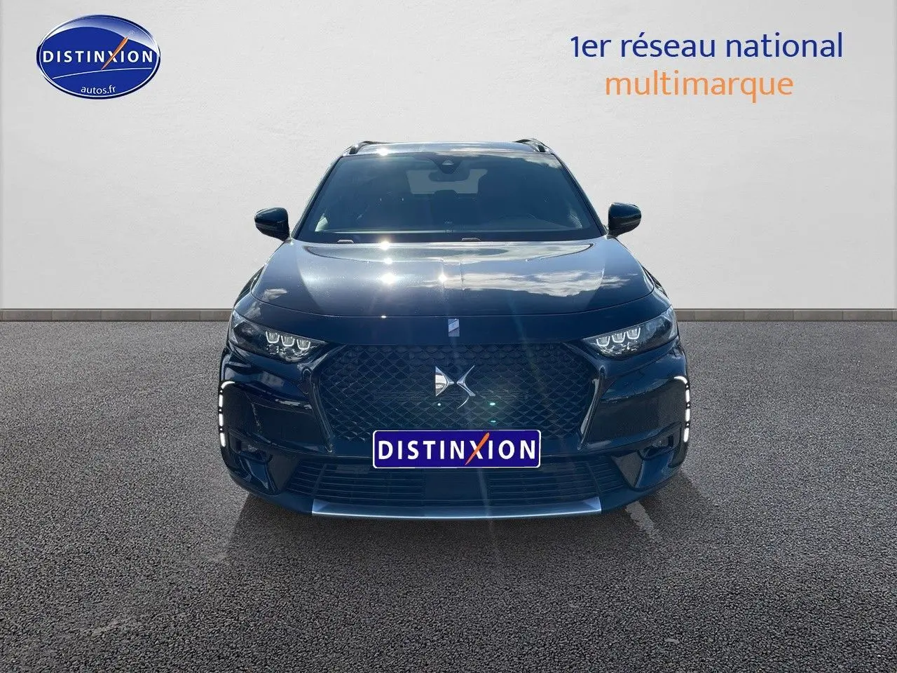 Vue frontale d'un DS7 Crossback E-TENSE noir perle métal avec calandre distinctive et phares LED allumés.