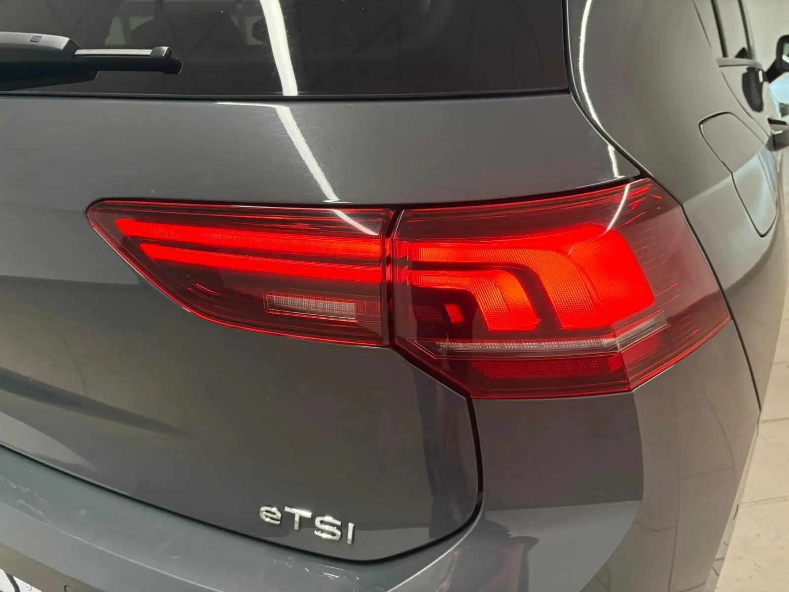 Feu arrière droit allumé sur Volkswagen Golf 1.5 eTSI gris dauphin vue arrière en gros plan.