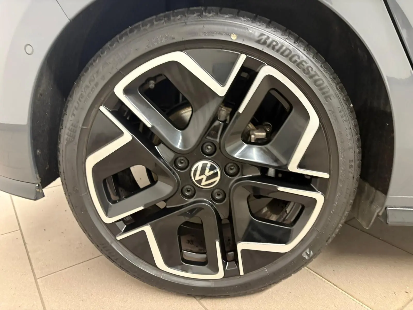 Gros plan sur la jante noire et argentée d'une Volkswagen Golf Gris Dauphin, côté avant droit.