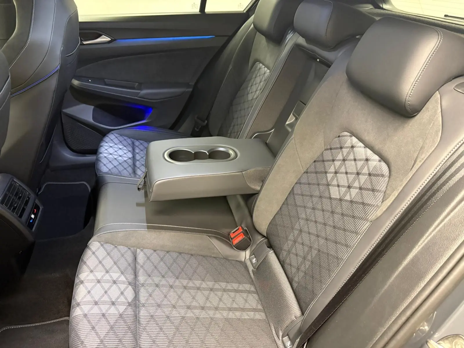 Vue intérieure côté droit des sièges arrière gris avec accoudoir central et porte-gobelets sur Volkswagen Golf 2025 R-Line Edition.