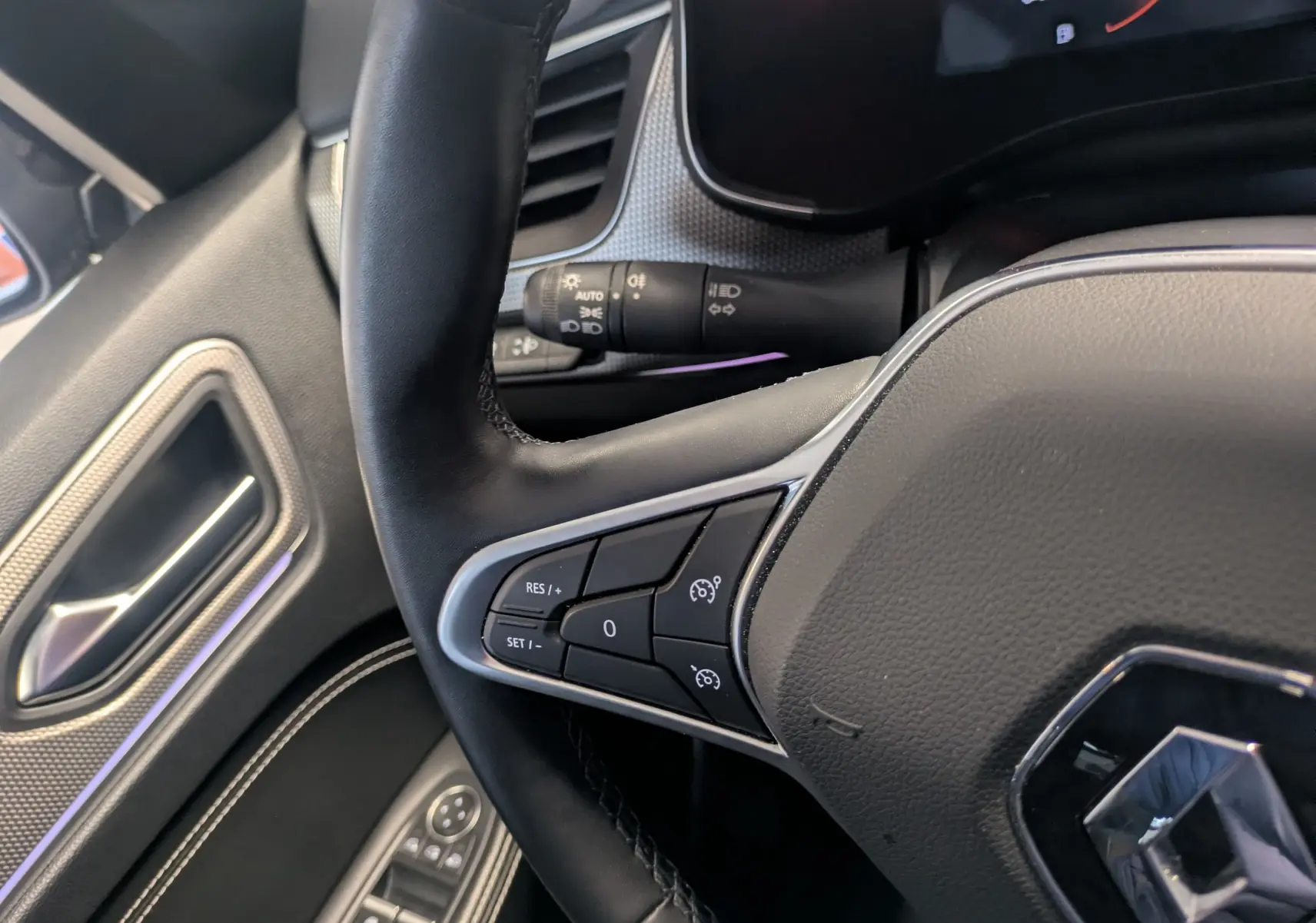 Gros plan sur le volant noir de la Renault Arkana 2023 avec commandes de régulateur de vitesse côté gauche.