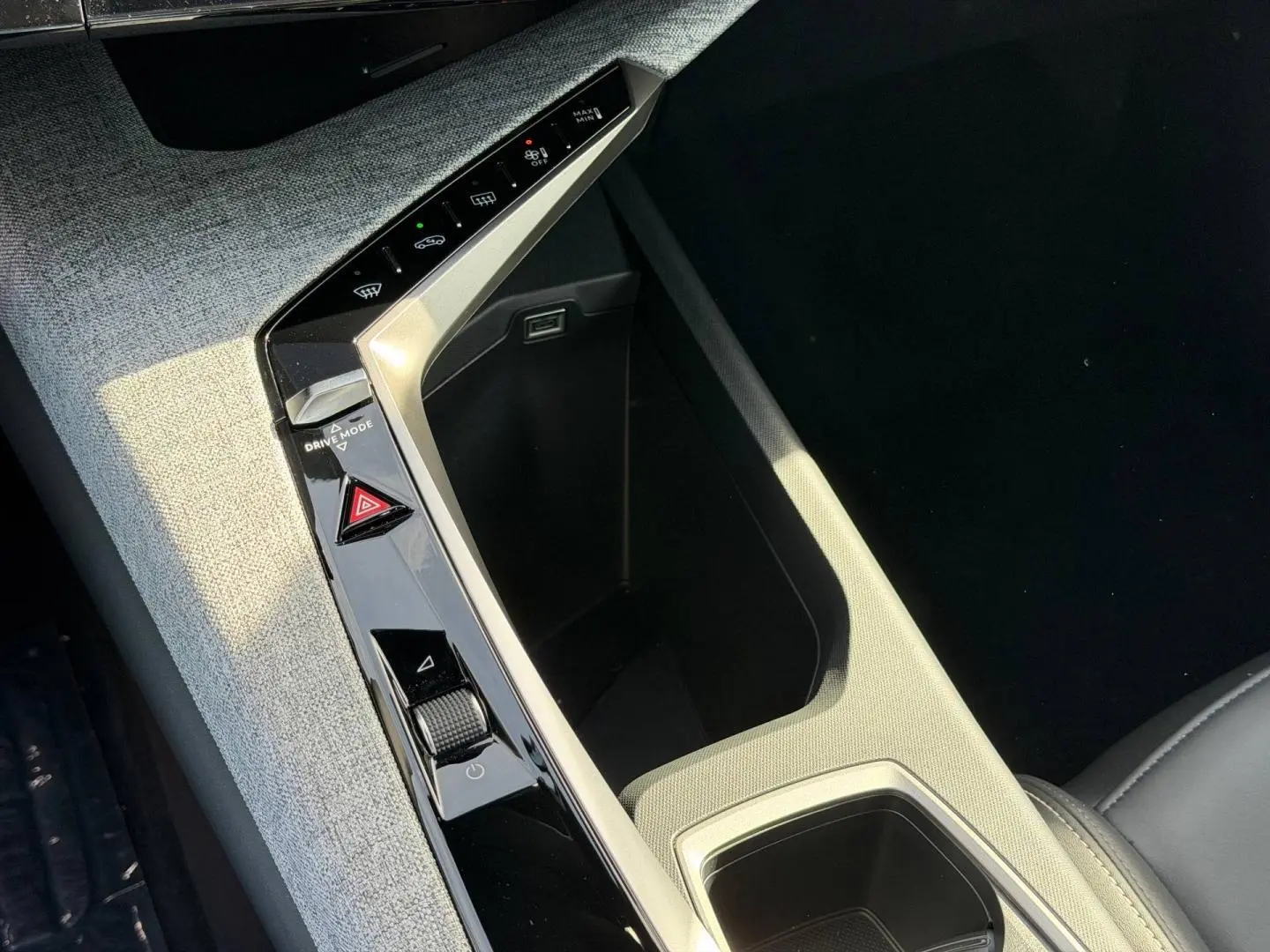 Gros plan sur la console centrale du Peugeot 3008 2026, avec tissu gris clair et commandes tactiles noires.