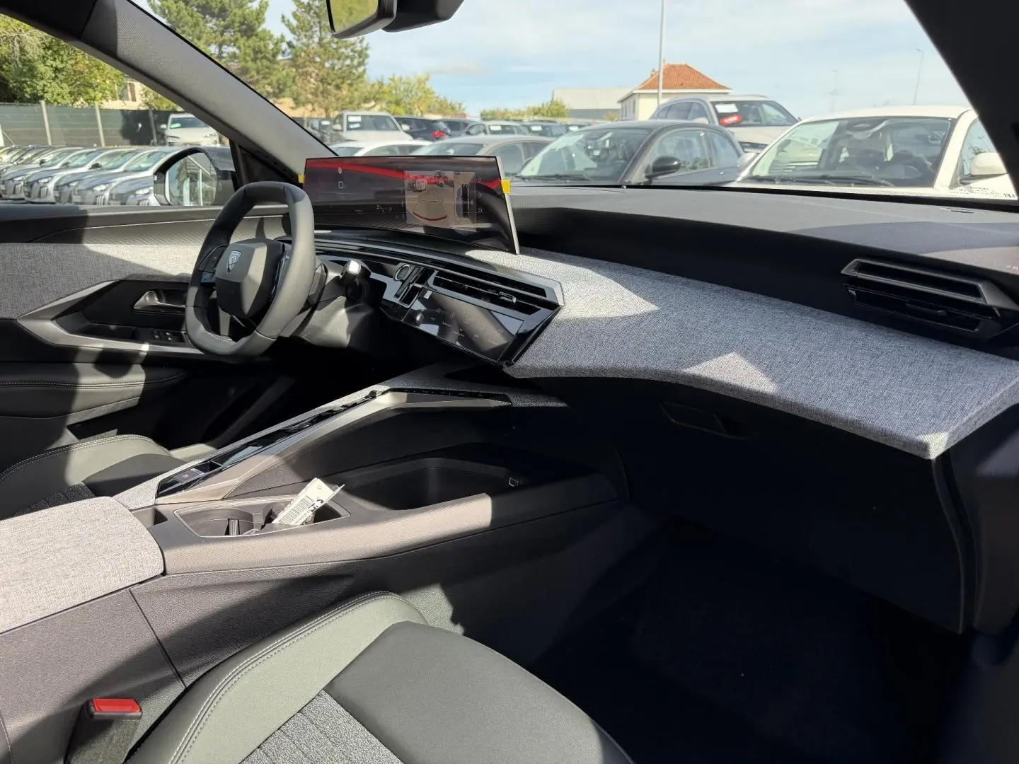 Vue intérieure côté passager du Peugeot 3008 2026, tableau de bord avec habillage tissu gris clair et écran tactile flottant.