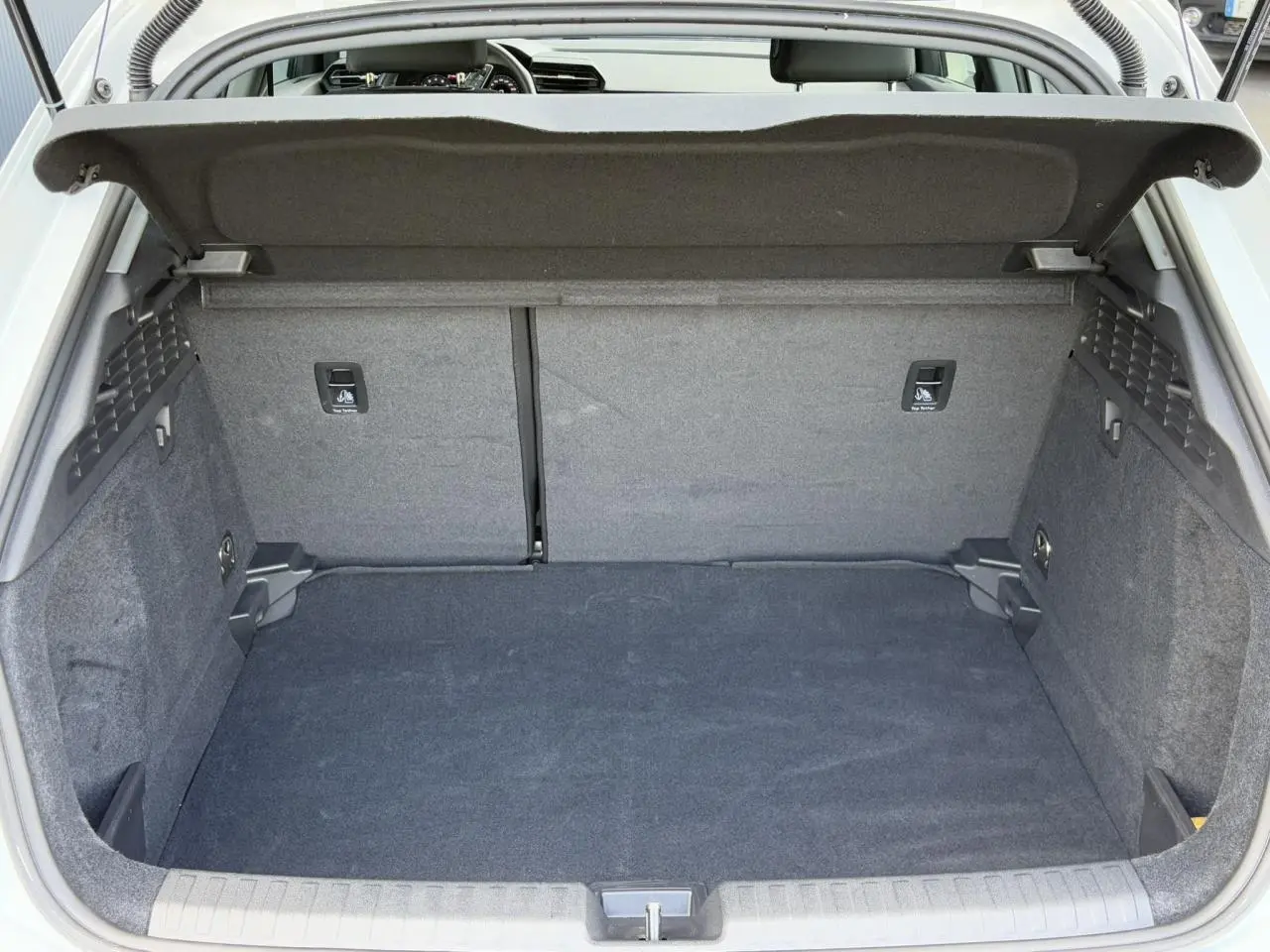 Coffre ouvert vu de l'arrière d'une Audi A3 Sportback blanc Arkona, espace de chargement propre et spacieux.