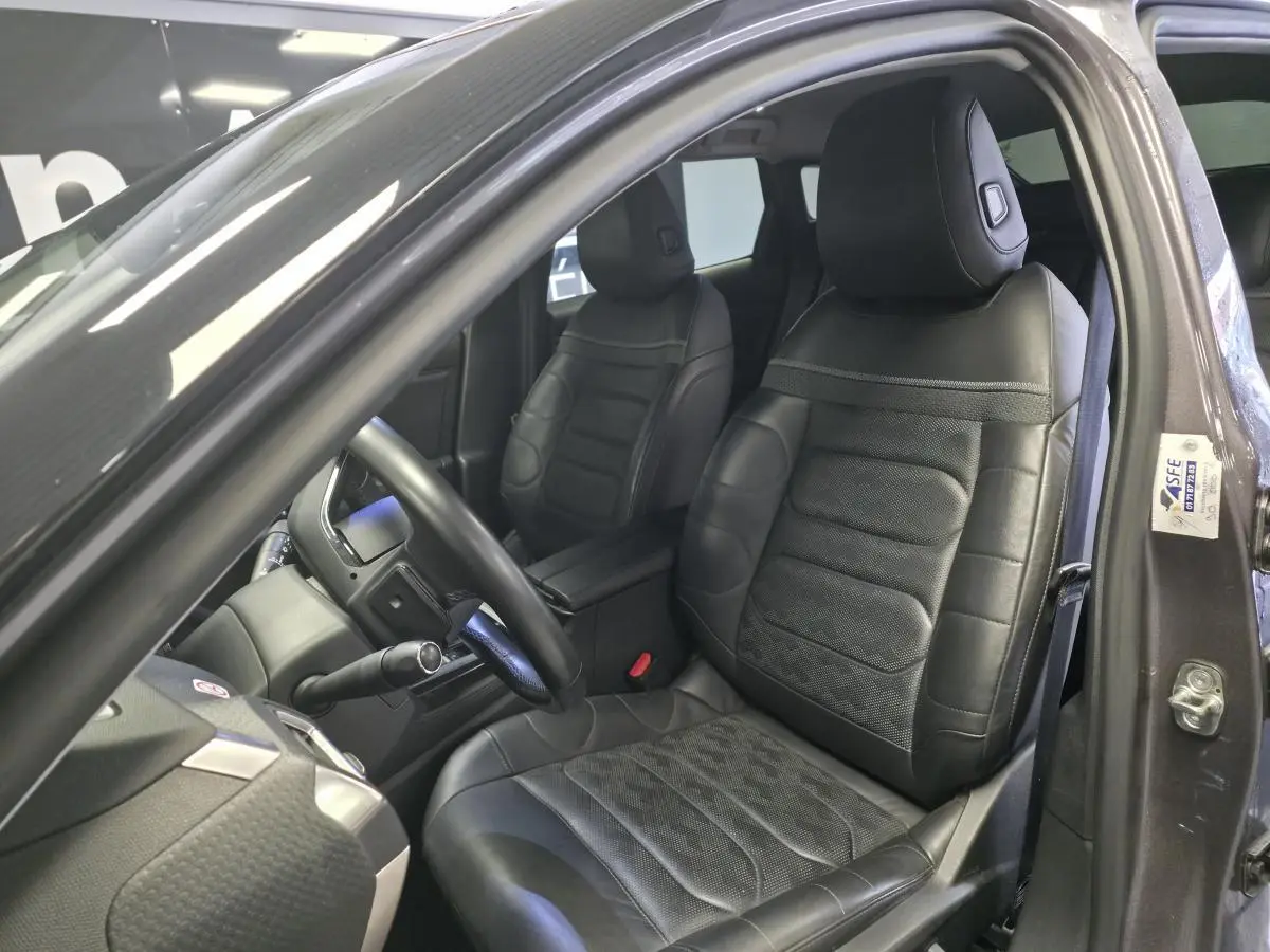 Intérieur de la Citroën C5 X hybride 2023, vue côté conducteur, sièges cuir noir perforé avec motifs chevron.