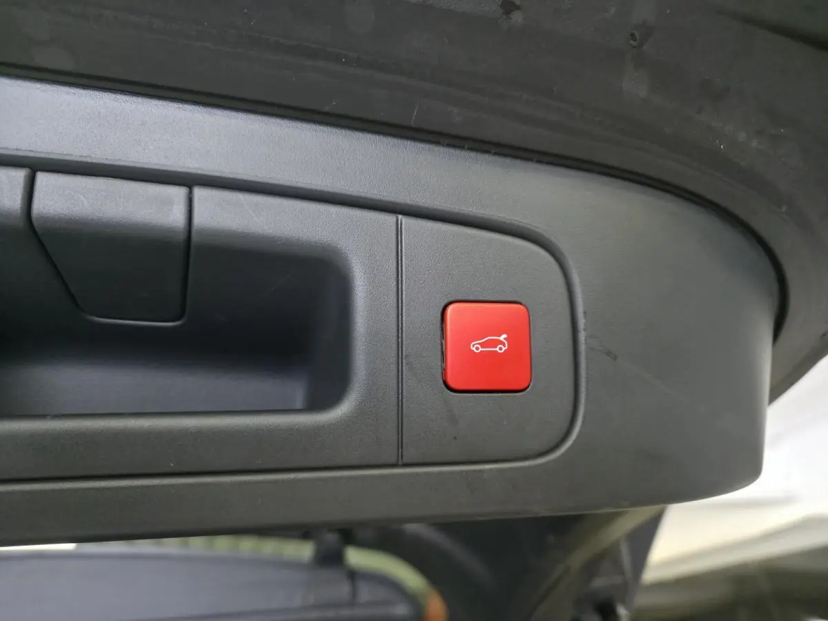 Gros plan sur le bouton rouge d'ouverture électrique du hayon du Citroën C5 X hybride rechargeable gris.