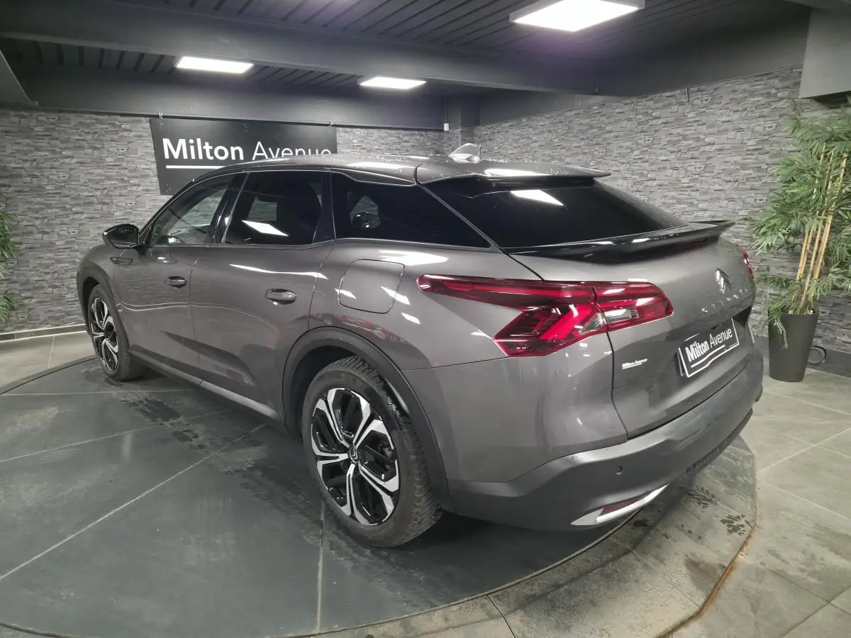 Vue 3/4 arrière droite d'une Citroën C5 X hybride rechargeable gris métallisé avec jantes alliage et vitres teintées.