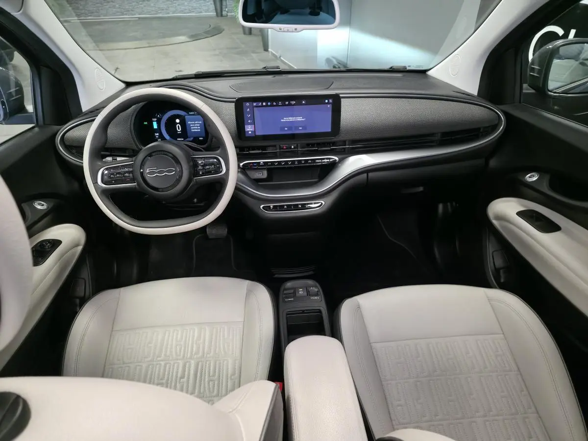 Intérieur avant de la Fiat 500 Cabriolet électrique 2022, tableau de bord moderne et sièges en éco-cuir clair avec volant bicolore.
