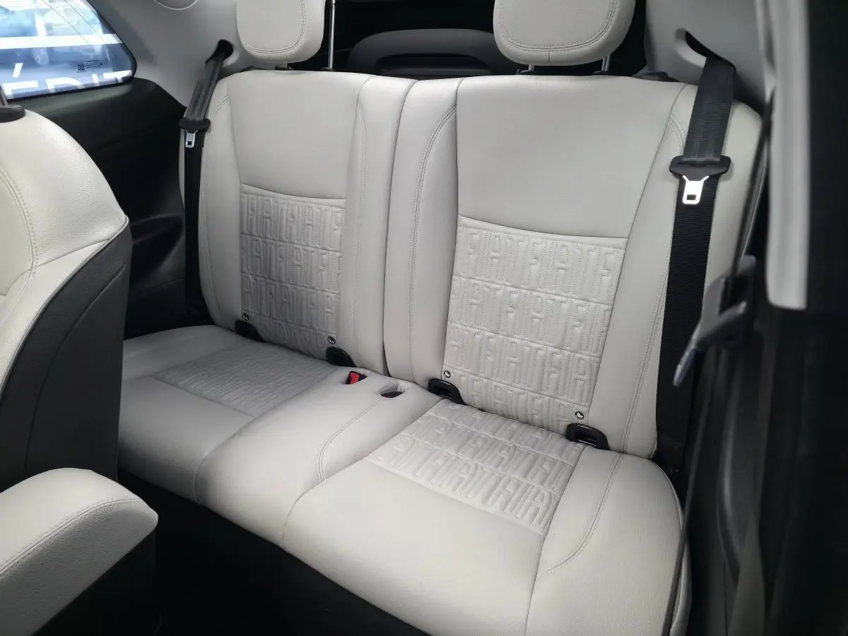 Vue rapprochée de la banquette arrière beige clair avec motifs FIAT embossés dans une Fiat 500 Cabriolet électrique.