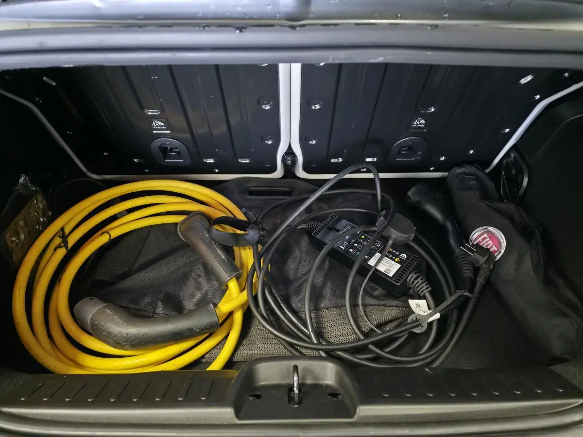 Coffre ouvert d'une FIAT 500 Cabriolet électrique gris foncé, montrant câbles de recharge jaune et noir rangés.