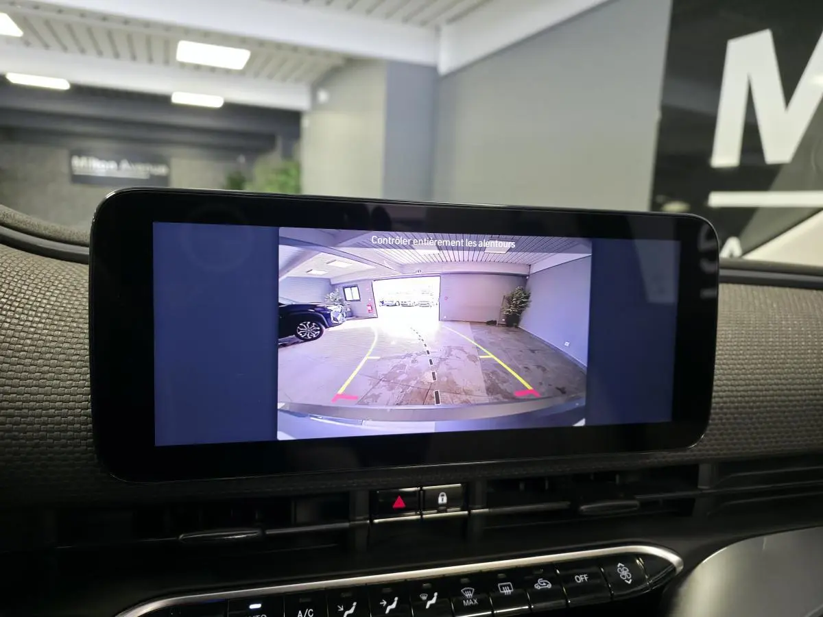 Écran central montrant la caméra de recul d'une Fiat 500 Cabriolet électrique gris foncé dans un garage.