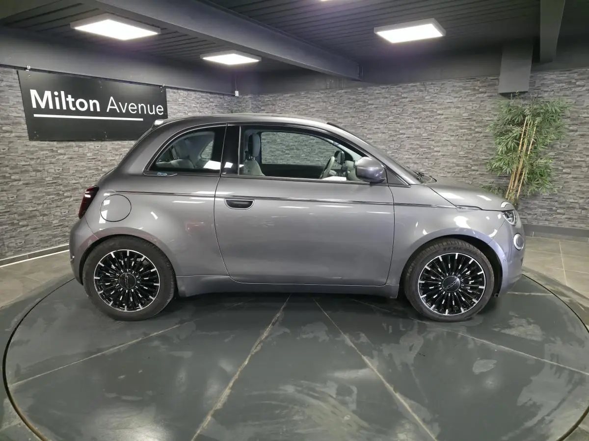 Profil droit de la Fiat 500 Cabriolet électrique 2022 gris foncé avec jantes alliage bicolores en showroom.