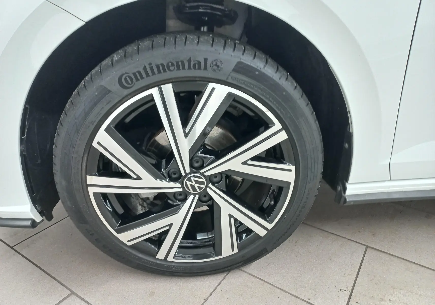 Gros plan sur la roue avant droite d'une Volkswagen Polo Blanc Pur avec jante alliage noire et argentée R-Line.