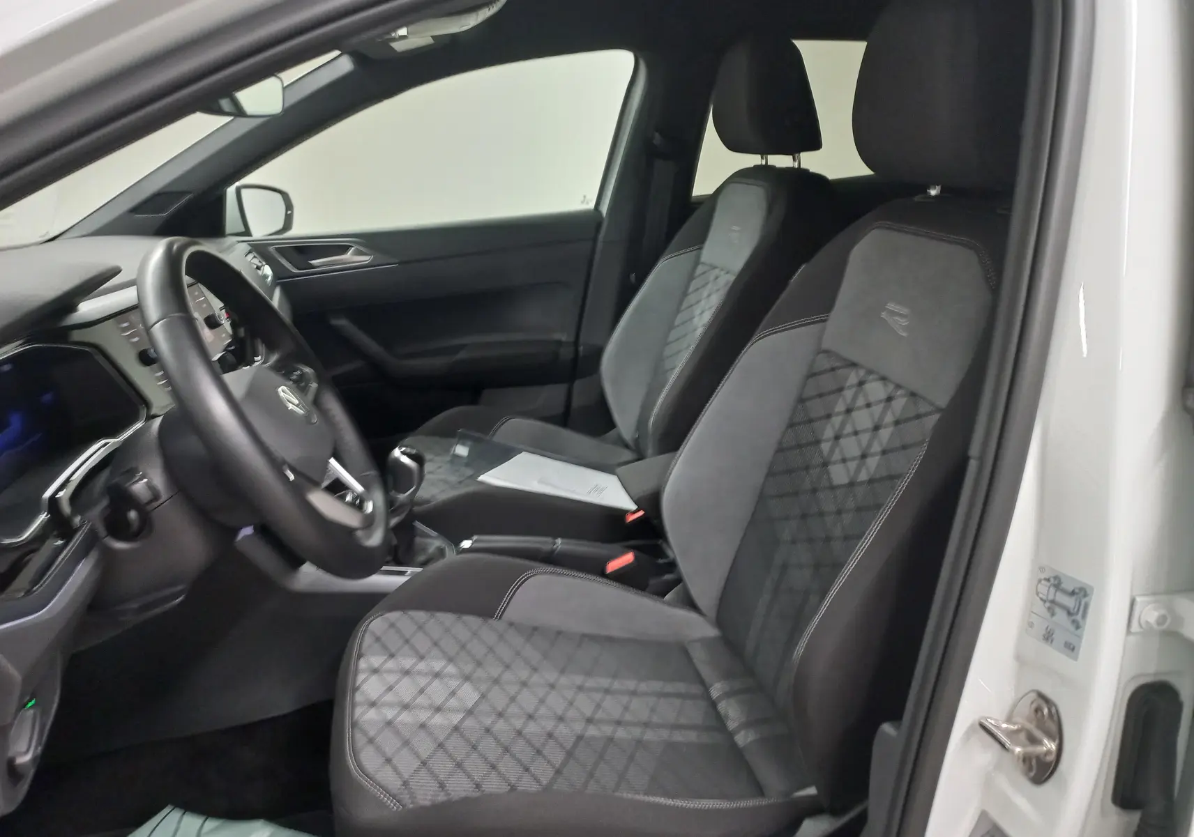 Intérieur avant droit d'une Volkswagen Polo blanc pur 2025, sièges R-Line en tissu et alcantara avec volant cuir.